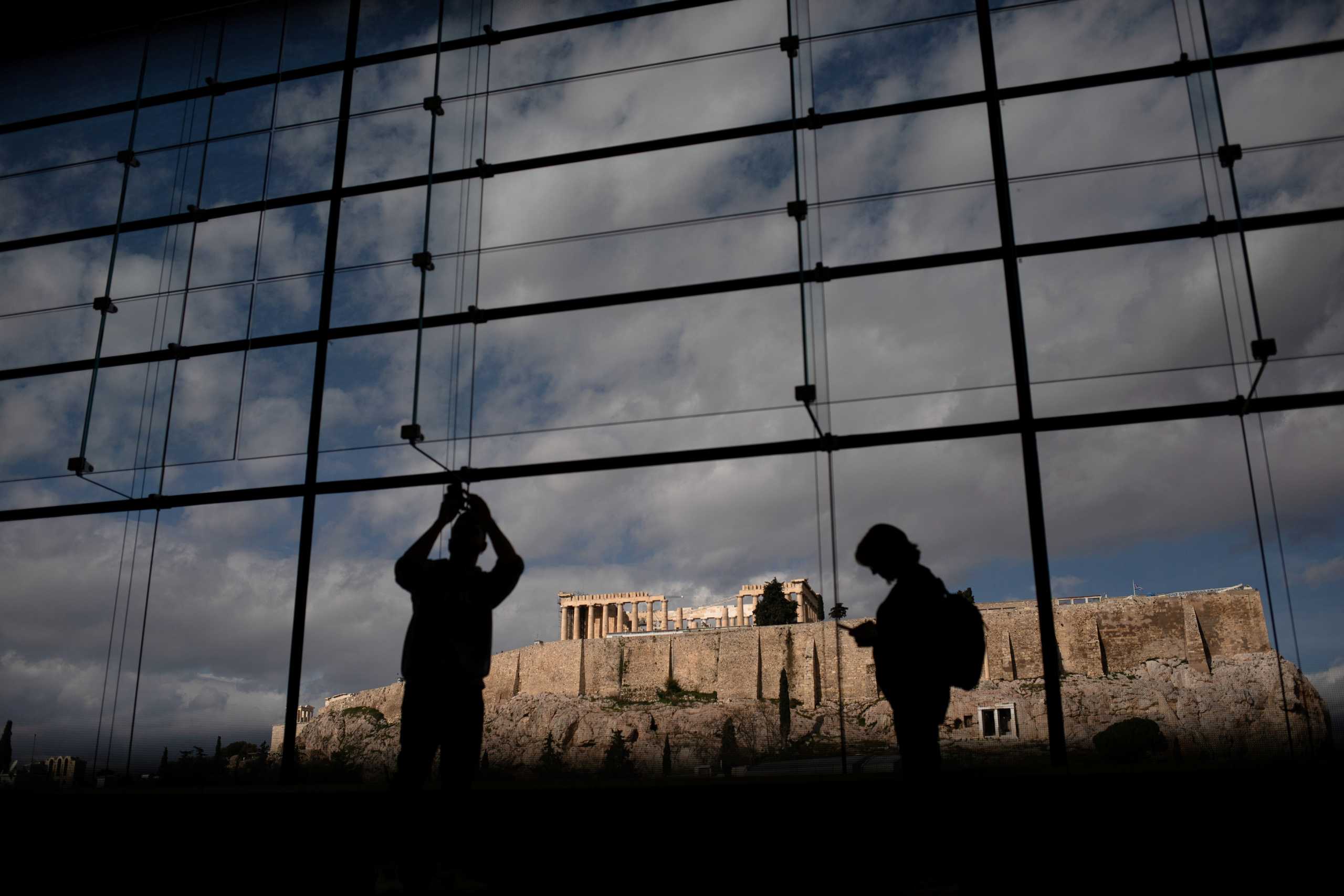 FILE PHOTO: Visitors take pictures of the Parthenon temple seen in the background, as they visit the Parthenon Gallery of the Acropolis Museum, in Athens, Greece, January 29, 2020. Picture taken January 29, 2020. REUTERS