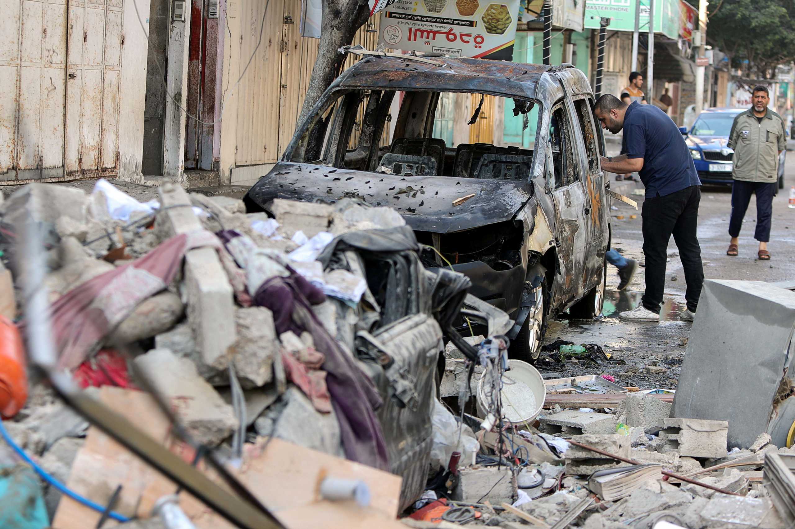 A Palestinian man inspects a damaged vehicle in the aftermath of an Israeli air strike on a house, amid Israeli-Palestinian fighting, in Gaza City, May 19, 2021. REUTERS