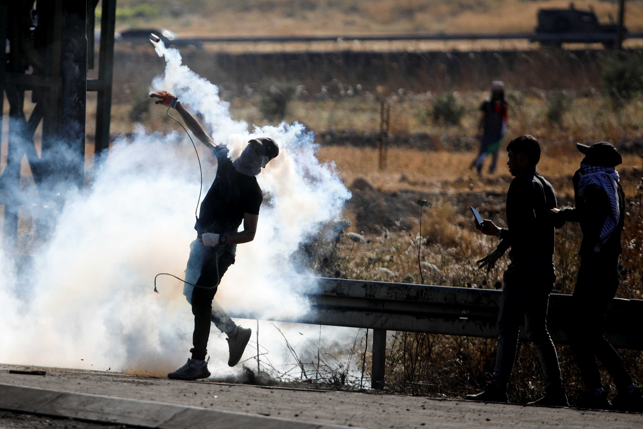 A Palestine protestor throws back a tear gas grenade during an anti-Israel protest over cross-border violence between Palestinian militants in Gaza and the Israeli military, near Hawara checkpoint near Nablus in the Israeli-occupied West Bank, May 18, 2021. REUTERS