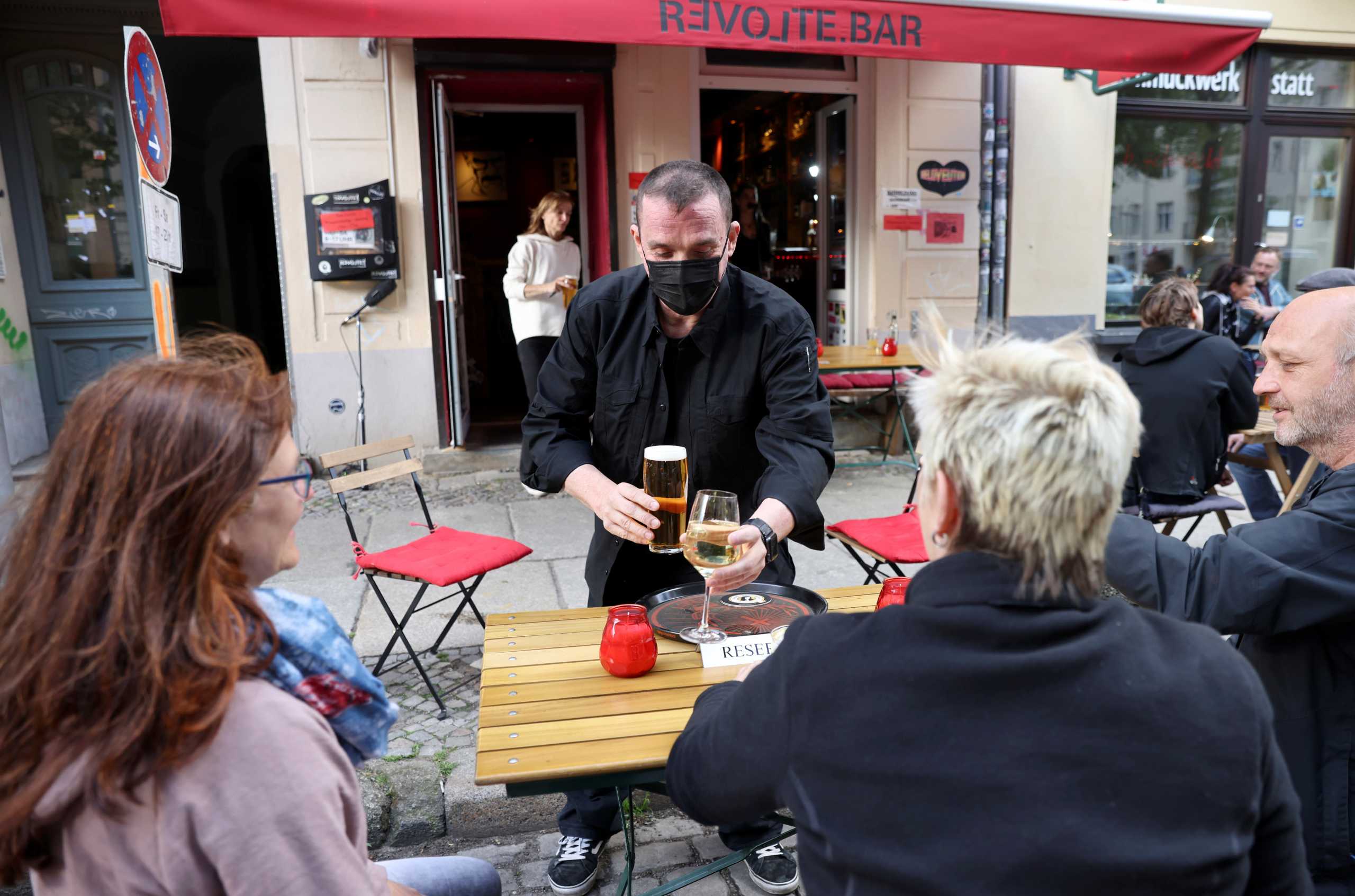 Michael Hanschke of Revolte bar serves customers, as cafes, bars and restaurants reopen their terraces after being closed down for months, amid the coronavirus disease (COVID-19) outbreak, in Berlin, Germany, May 21, 2021. REUTERS