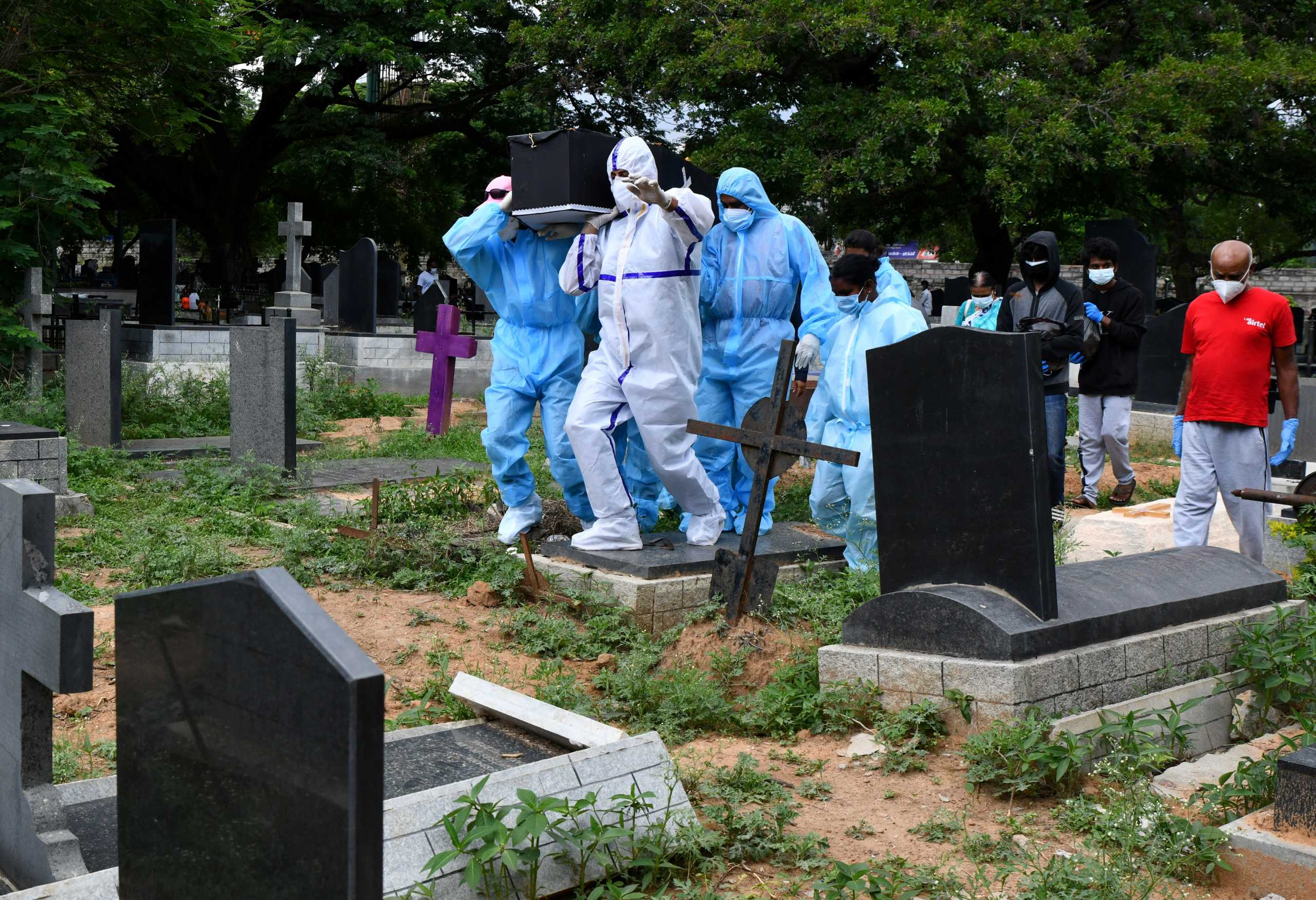 Akshay Mandlik, 37, a professor and a volunteer, wearing personal protective equipment (PPE) along with other volunteers carry the body of a person, who died from the coronavirus disease (COVID-19), for burial at a cemetery in Bengaluru, India, May 18, 2021. Picture taken May 18, 2021. REUTERS