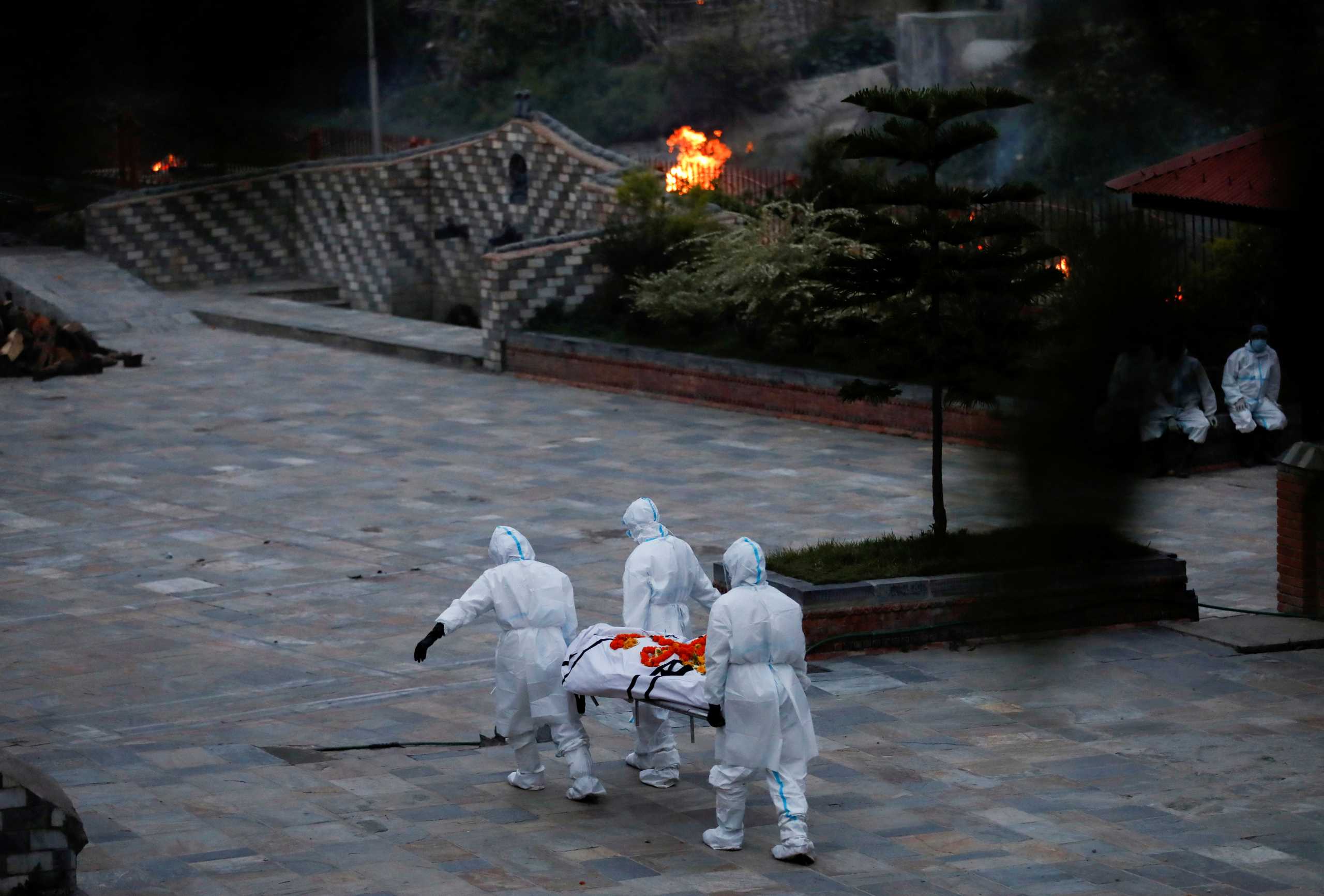 FILE PHOTO: Men wearing personal protective equipment (PPE) carry the body of a coronavirus disease (COVID-19) victim at the crematorium as the country recorded the highest daily increase in deaths since the pandemic began, in Kathmandu, Nepal May 3, 2021. REUTERS