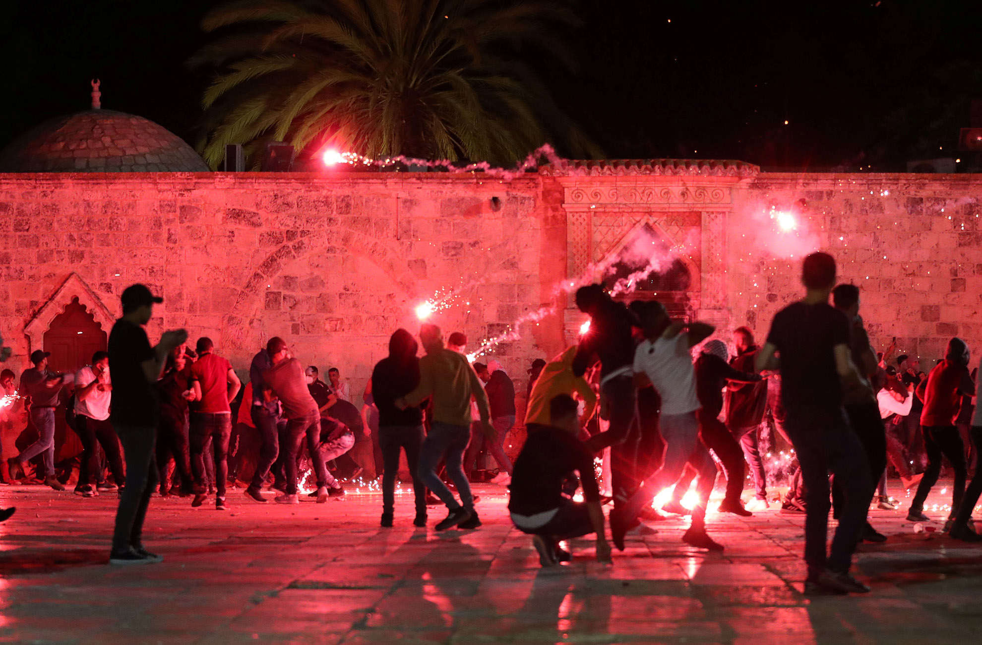 Palestinians react as Israeli police fire stun grenades during clashes at the compound that houses Al-Aqsa Mosque, known to Muslims as Noble Sanctuary and to Jews as Temple Mount, amid tension over the possible eviction of several Palestinian families from homes on land claimed by Jewish settlers in the Sheikh Jarrah neighbourhood, in Jerusalem's Old City, May 7, 2021. REUTERS