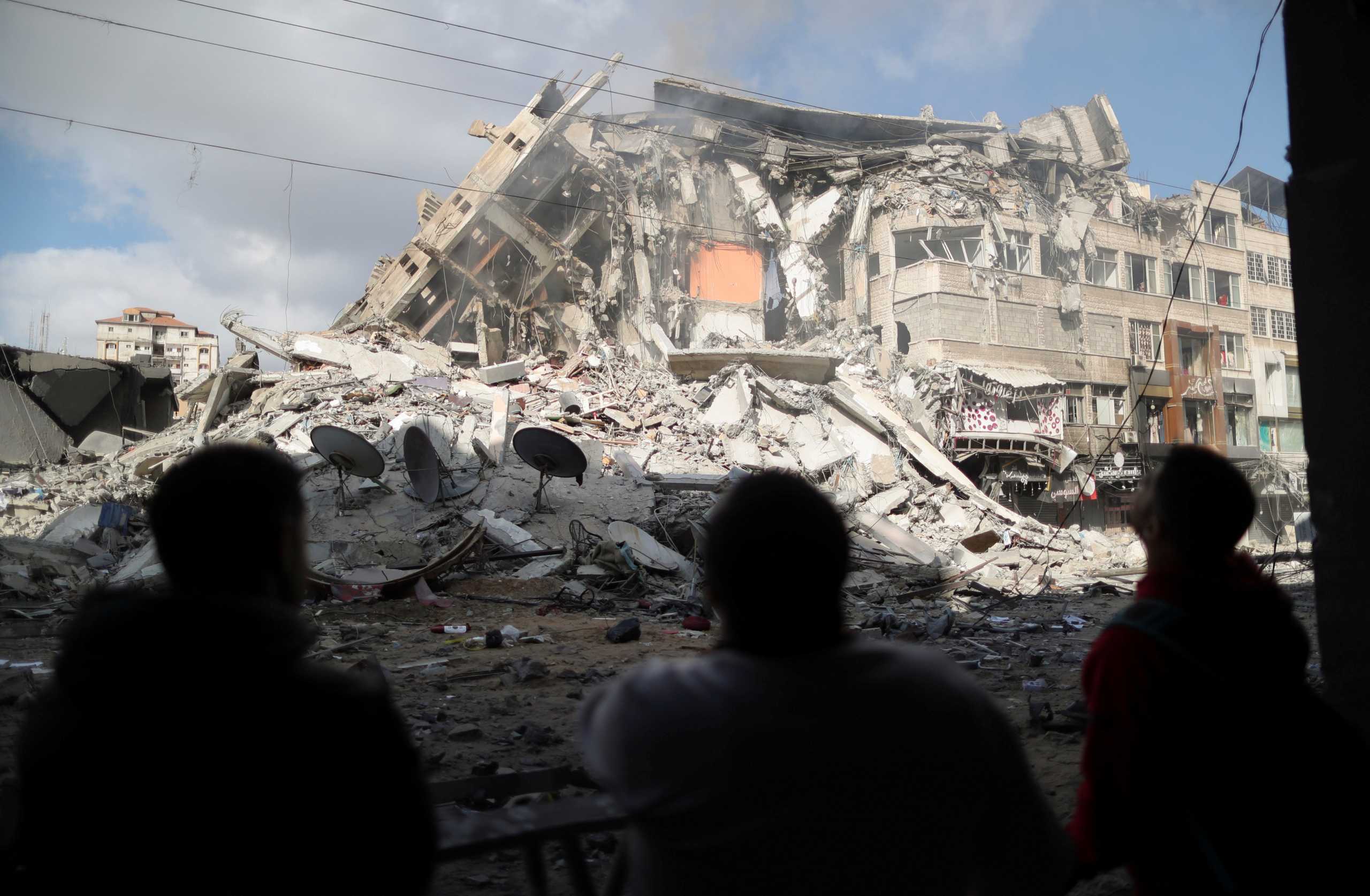 Palestinians look at the remains of a tower building which was destroyed by Israeli air strikes, amid a flare-up of Israeli-Palestinian violence, in Gaza City May 13, 2021. REUTERS