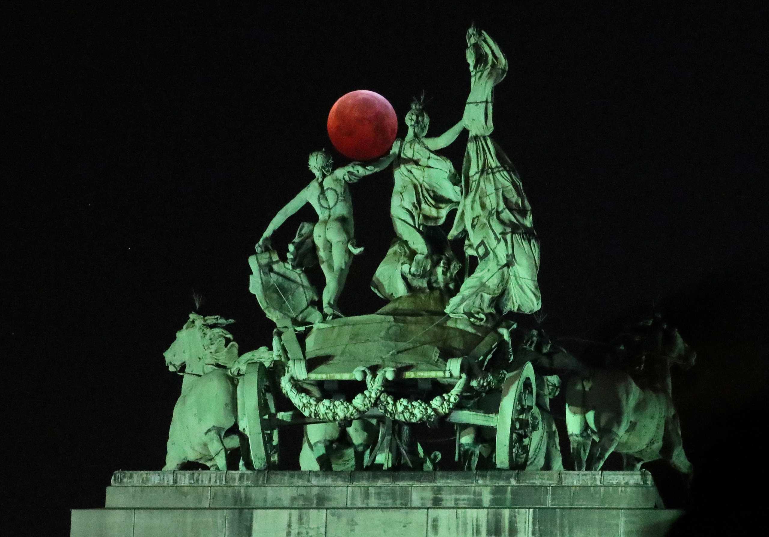 FILE PHOTO: The moon is seen beside a quadriga on the top of the Cinquantenaire arch during a total lunar eclipse, known as the "Super Blood Wolf Moon", in Brussels, Belgium January 21, 2019. REUTERS