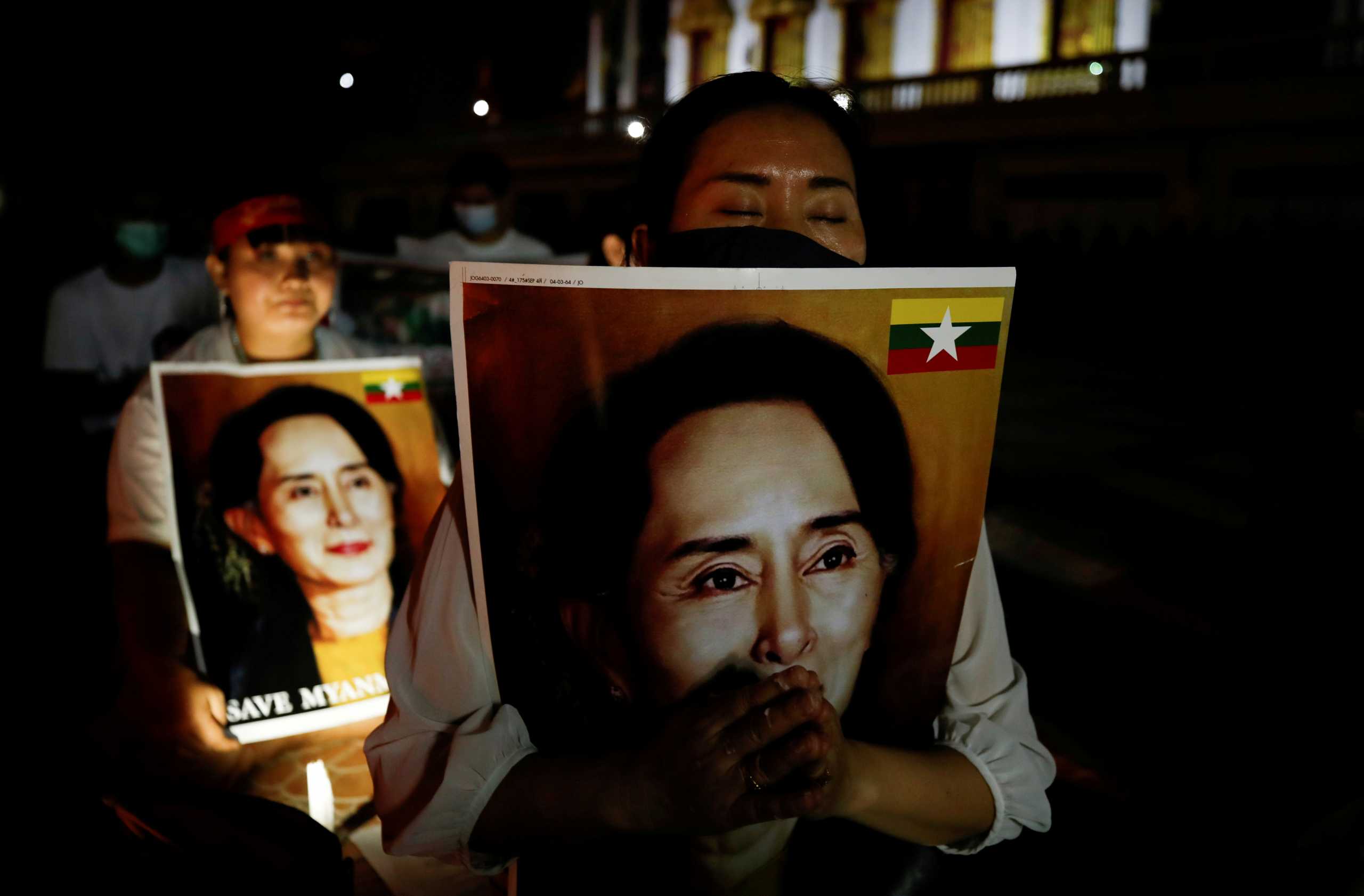 FILE PHOTO: Migrants protesting against the military junta in Myanmar hold pictures of leader Aung San Suu Kyi, during a candlelight vigil at a Buddhist temple in Bangkok, Thailand, March 28, 2021. REUTERS