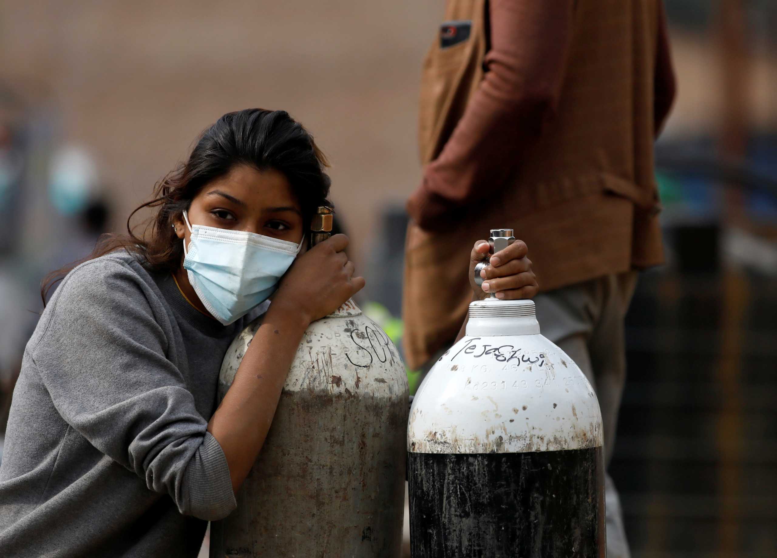 A woman holds on to the oxygen cylinders for a patient after refiling them at a factory, amidst the spread of coronavirus disease (COVID-19) surge as India's outbreak spreads across South Asia, in Kathmandu, Nepal May 9, 2021. REUTERS