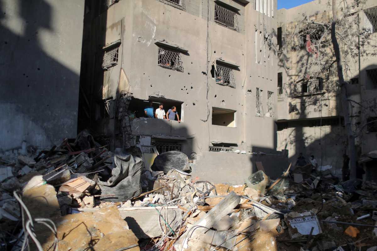 Palestinians look out of a damaged apartment near the site of a destroyed house in the aftermath of Israeli air strikes, amid a flare-up of Israeli-Palestinian violence, in Gaza City May 15, 2021. REUTERS