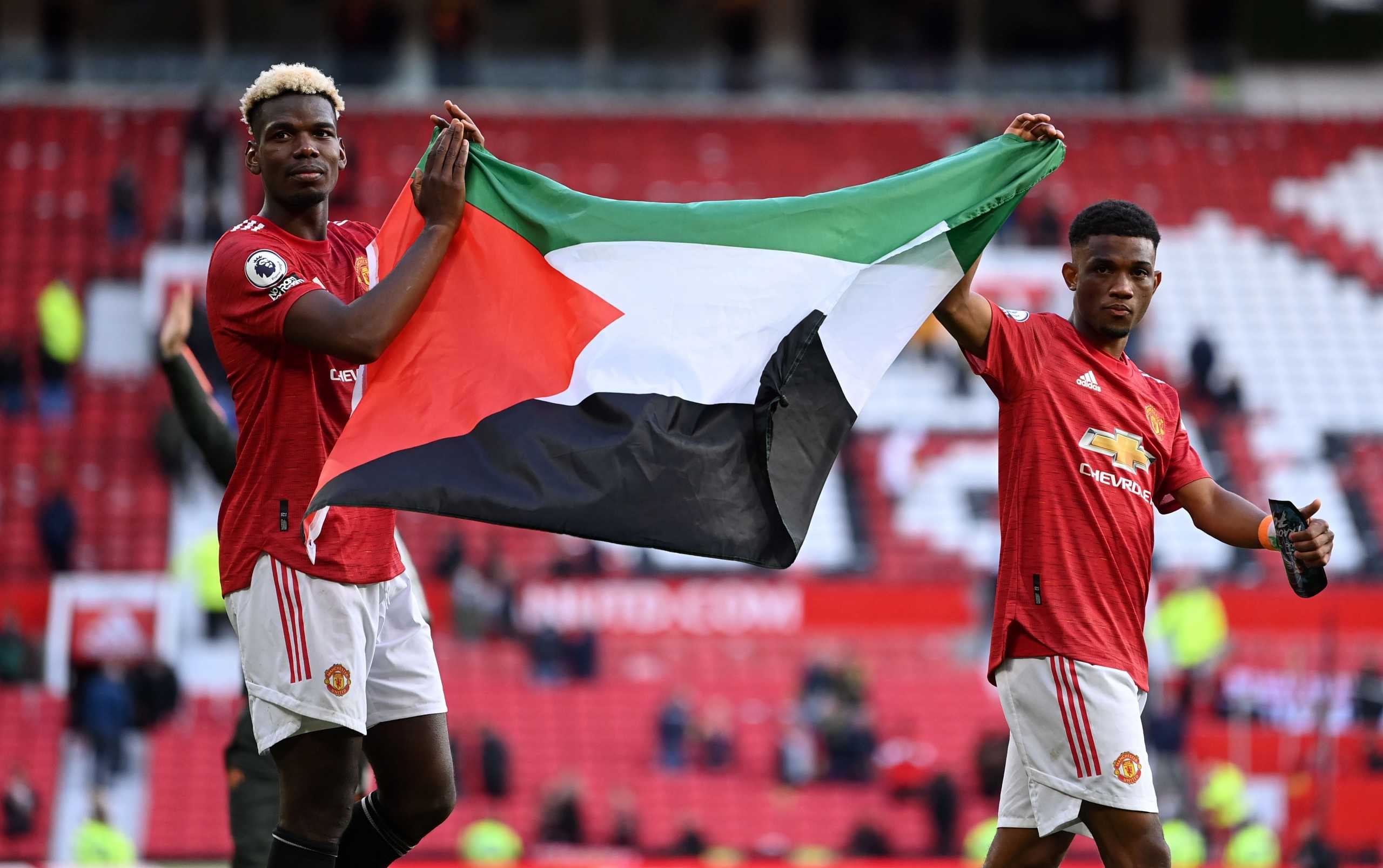 Soccer Football - Premier League - Manchester United v Fulham - Old Trafford, Manchester, Britain - May 18, 2021 Manchester United's Paul Pogba applauds fans while holding a Palestinian flag with Amad Diallo during a lap of appreciation after the match Pool via REUTERS