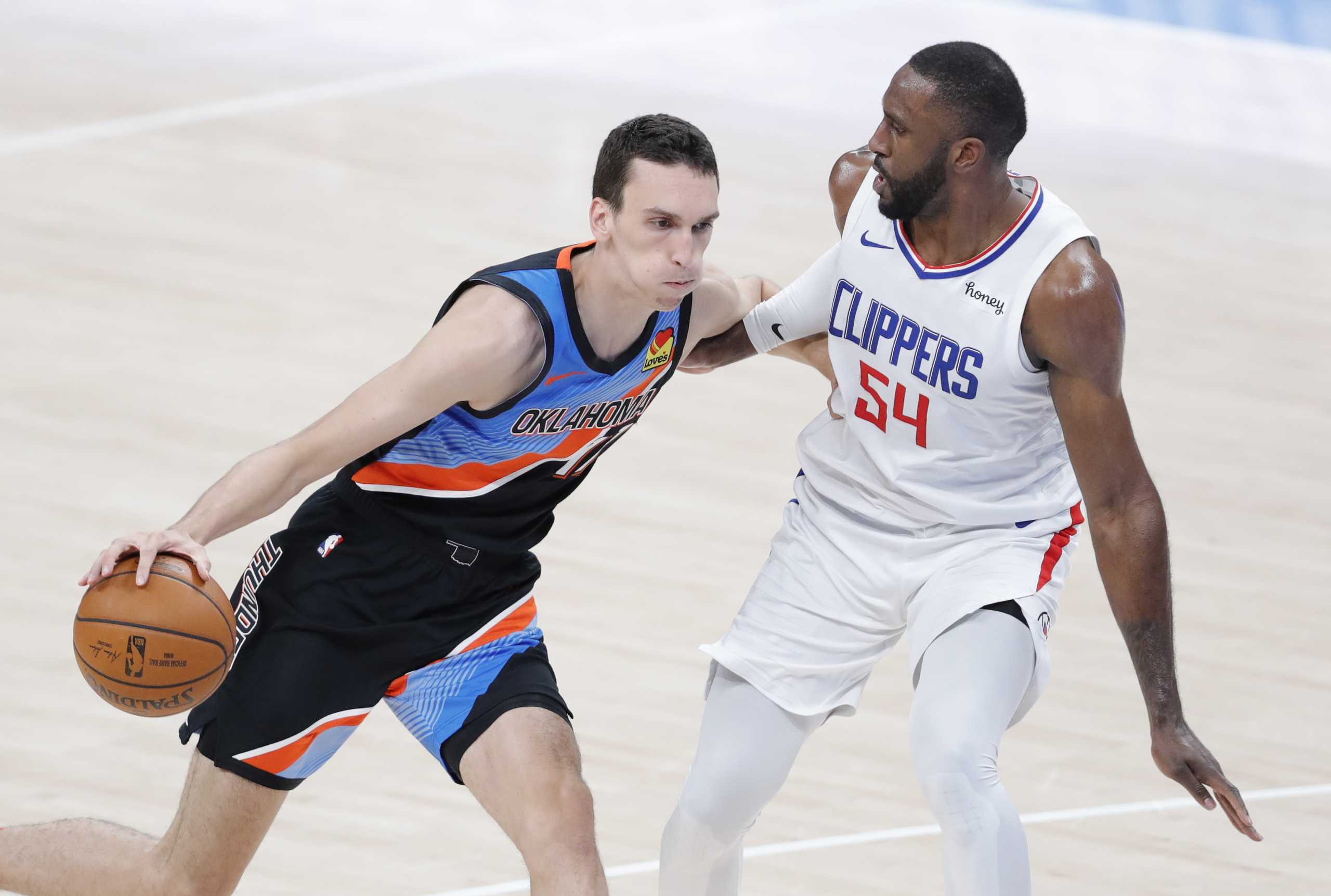 May 16, 2021; Oklahoma City, Oklahoma, USA; Oklahoma City Thunder forward Aleksej Pokusevski (17) drives to the basket as LA Clippers forward Patrick Patterson (54) defends during the first quarter at Chesapeake Energy Arena. Mandatory Credit: Alonzo Adams-USA TODAY Sports