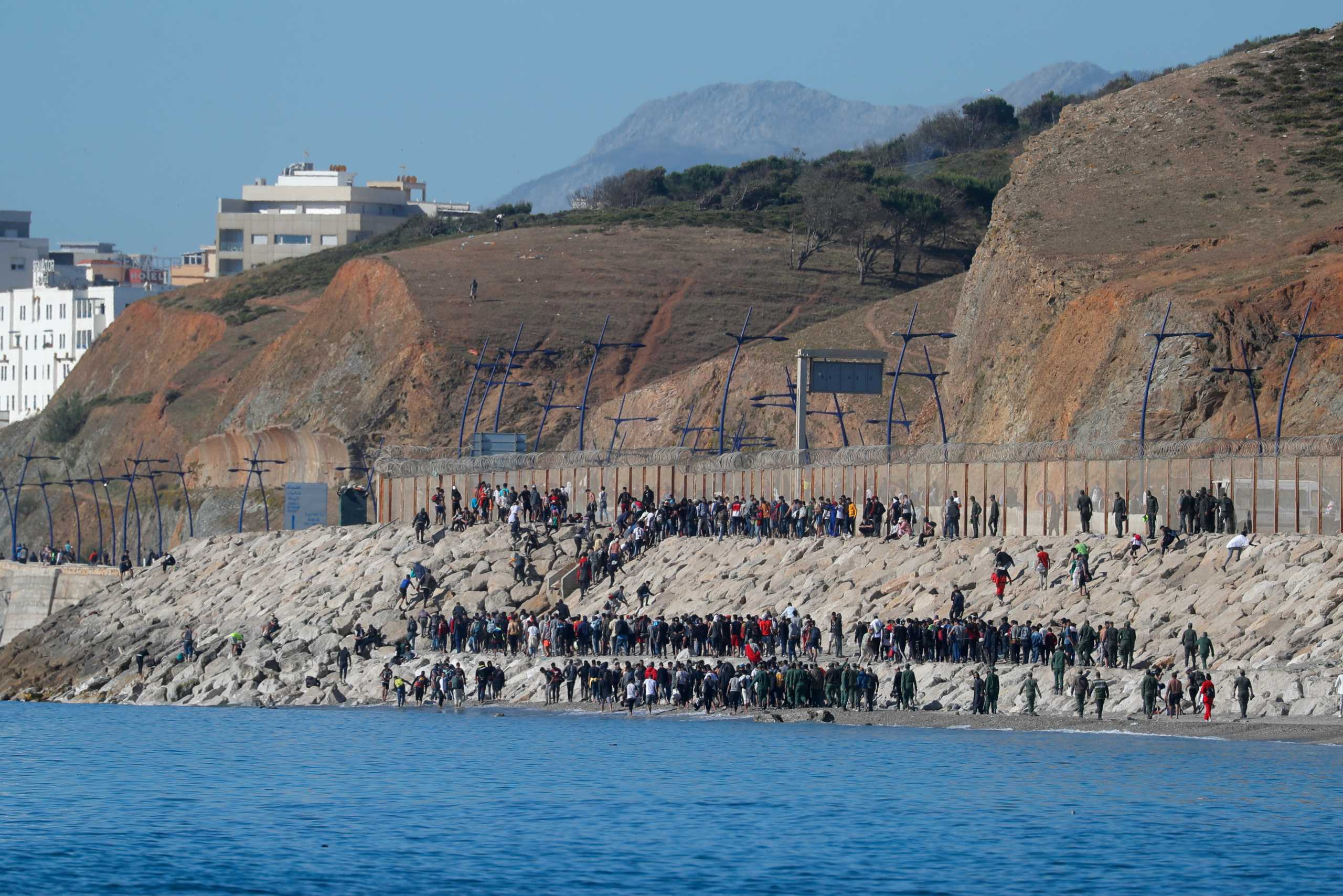 Migrants are led by Moroccan soldiers back to Morocco from El Tarajal beach, at the fence between the Spanish-Moroccan border, after thousands of migrants swam across the border, in Ceuta, Spain, May 19, 2021. REUTERS