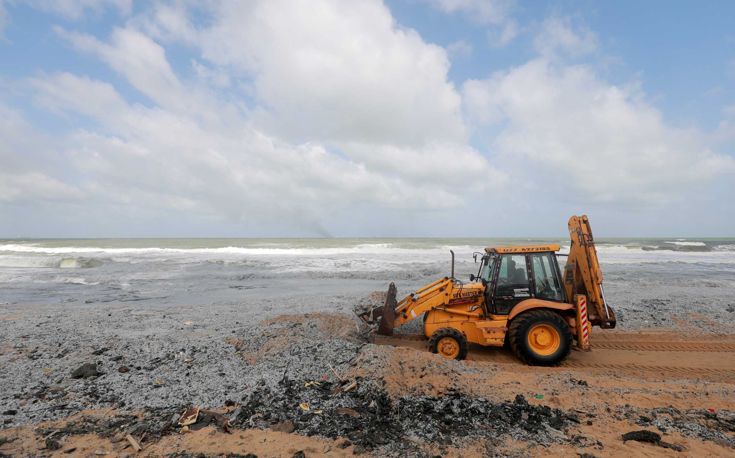 A backhoe loader collects debris washed off to a beach from the MV X-Press Pearl container ship, which caught fire off the Colombo Harbour, on a beach in Ja-Ela, Sri Lanka May 28, 2021. REUTERS