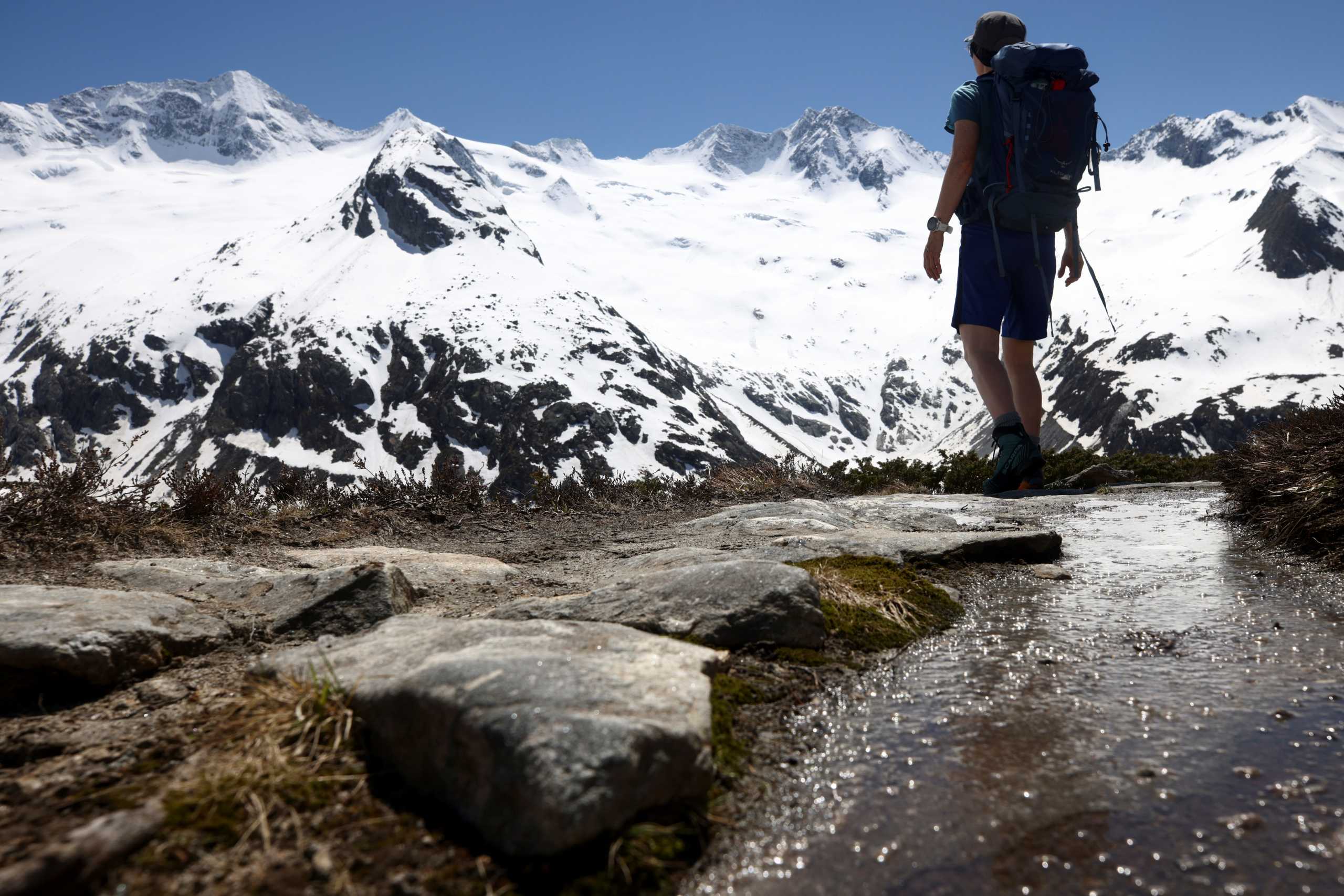 A hiker is seen in front of snow covered mountains in the Zillertal Alps, near the village of Ginzling, Austria, June 1, 2021. REUTERS