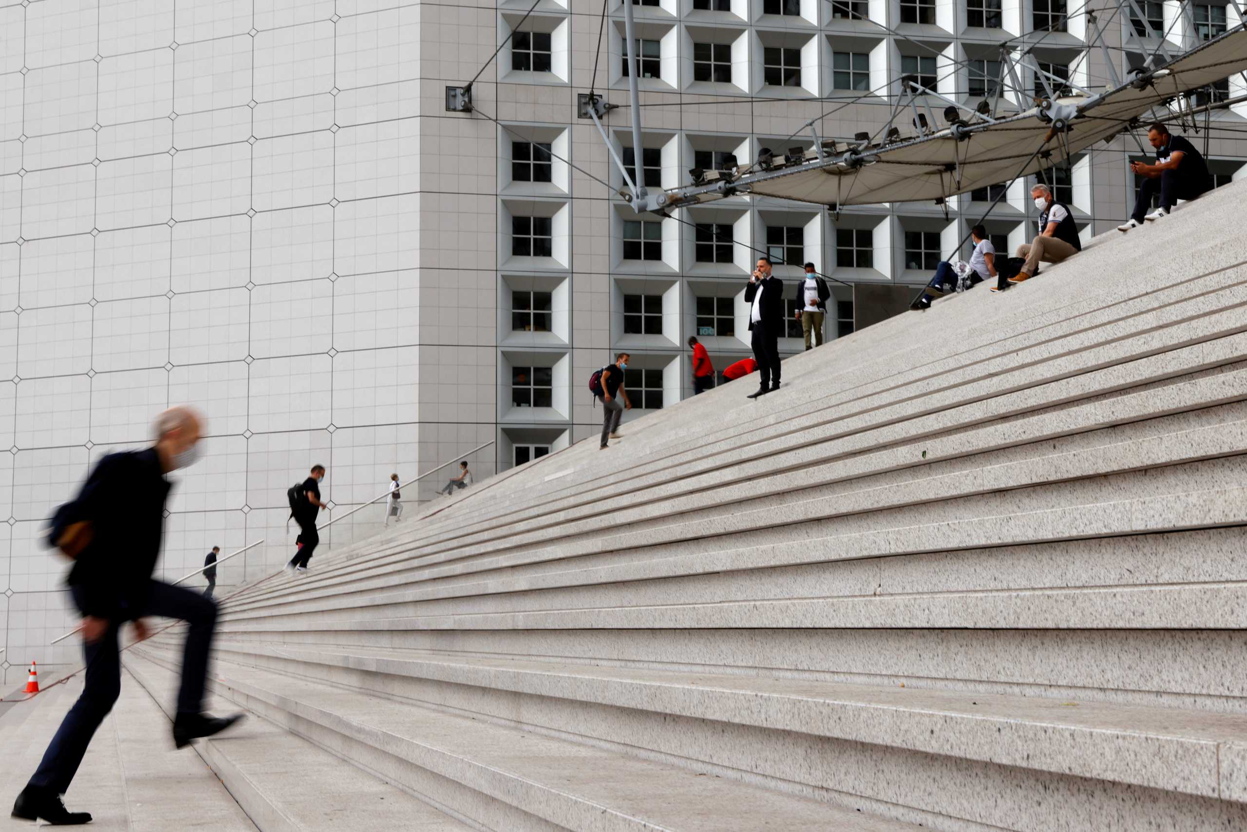 FILE PHOTO: People wearing protective face masks walk at the financial and business district of La Defense in Nanterre as work rules have been relaxed with working-from-home requirements gradually being lifted amid the coronavirus disease (COVID-19) outbreak in France, June 10, 2021.  REUTERS