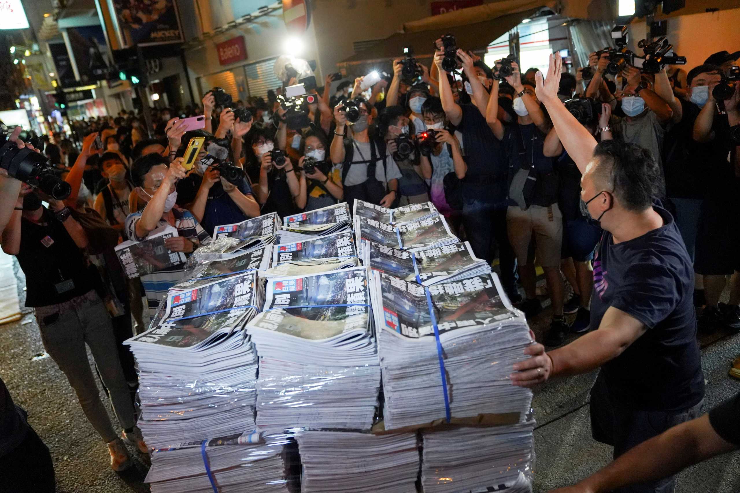 FILE PHOTO: A man gestures as he brings copies of the final edition of Apple Daily, published by Next Digital, to a news stand in Hong Kong, China June 24, 2021. REUTERS