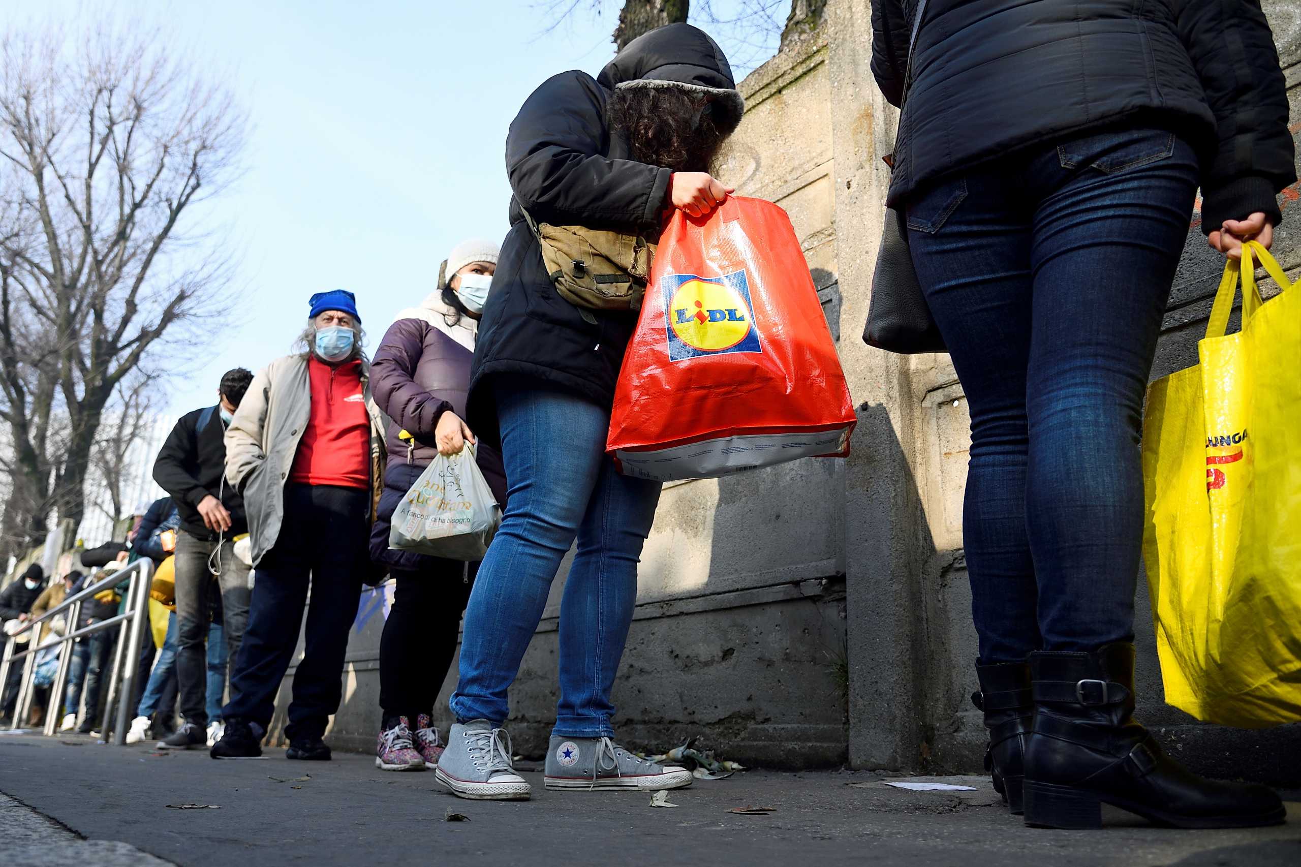 FILE PHOTO: People queue for free food as Italians struggle to cope in a tough economic climate amid the coronavirus pandemic in Milan, Italy, December 14, 2020. REUTERS
