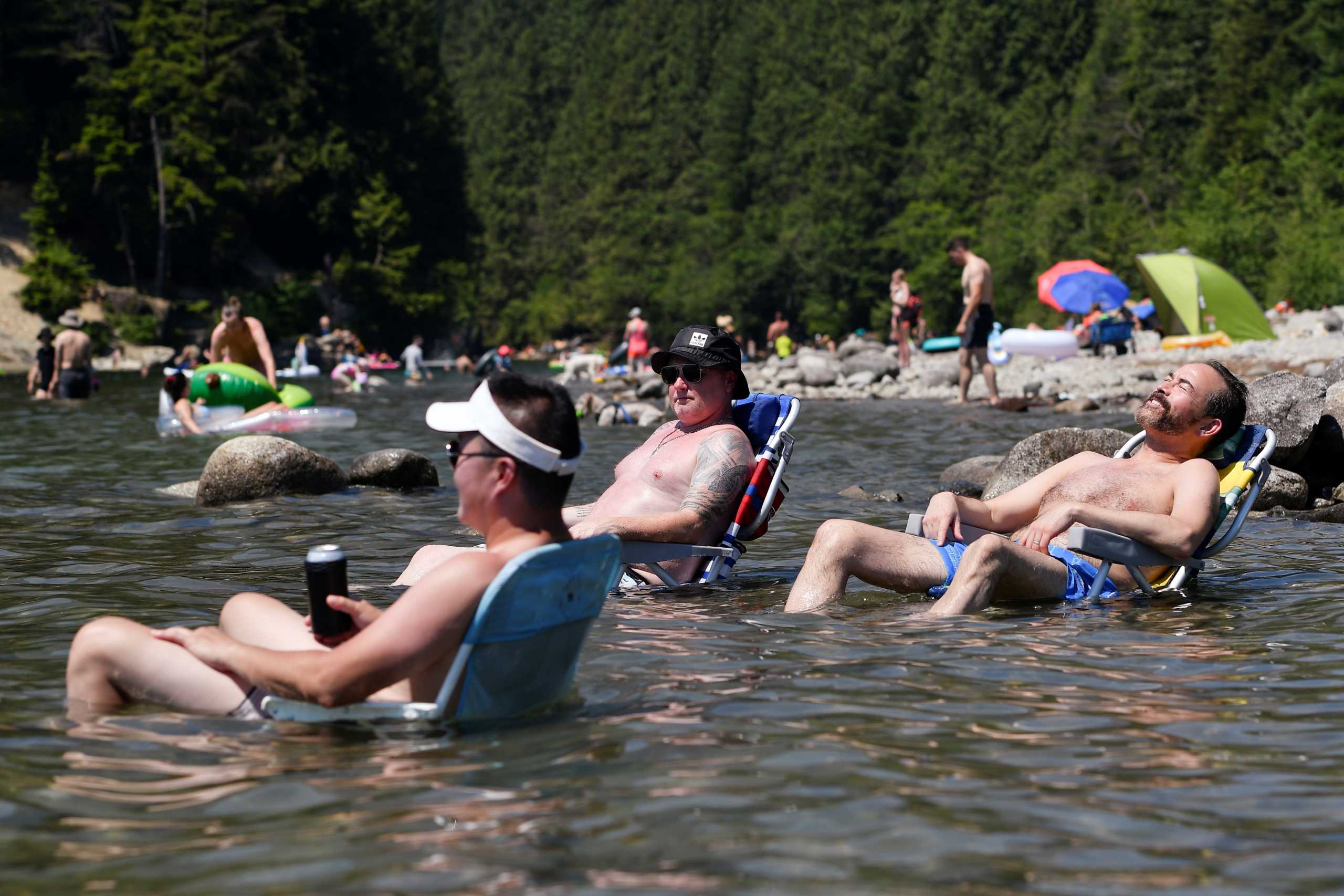 Beachgoers sit in the water at Alouette Lake to cool off during the scorching weather of a heatwave in Maple Ridge, British Columbia, Canada June 28, 2021. REUTERS