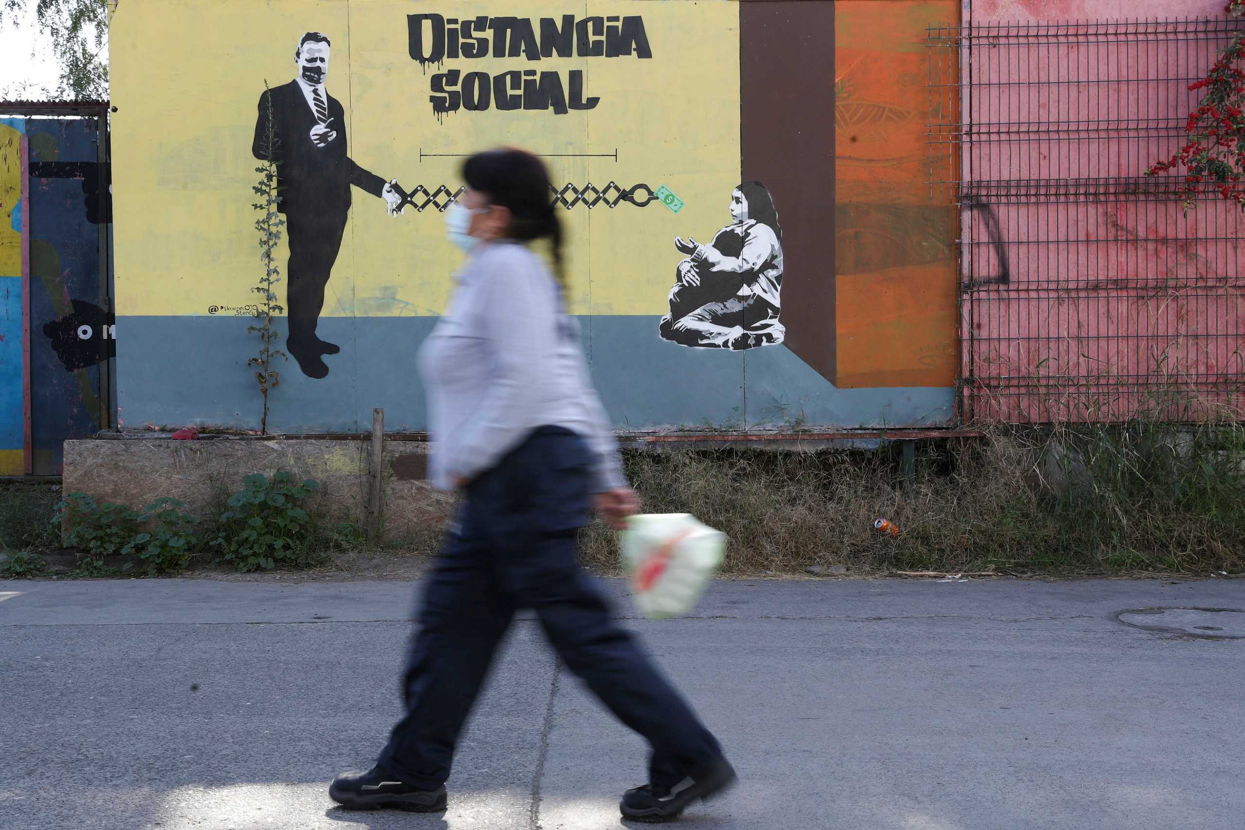 A woman walks past a graffiti reading 'Social distance' during the outbreak of the coronavirus disease (COVID-19) in Santiago, Chile June 7, 2021. REUTERS