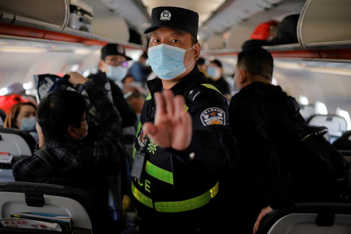 A police officer orders Reuters journalists off the plane before all other passengers without explanation while the plane is parked on the tarmac at Urumqi airport, Xinjiang Uyghur Autonomous Region, China, May 5, 2021. Picture taken May 5, 2021. REUTERS