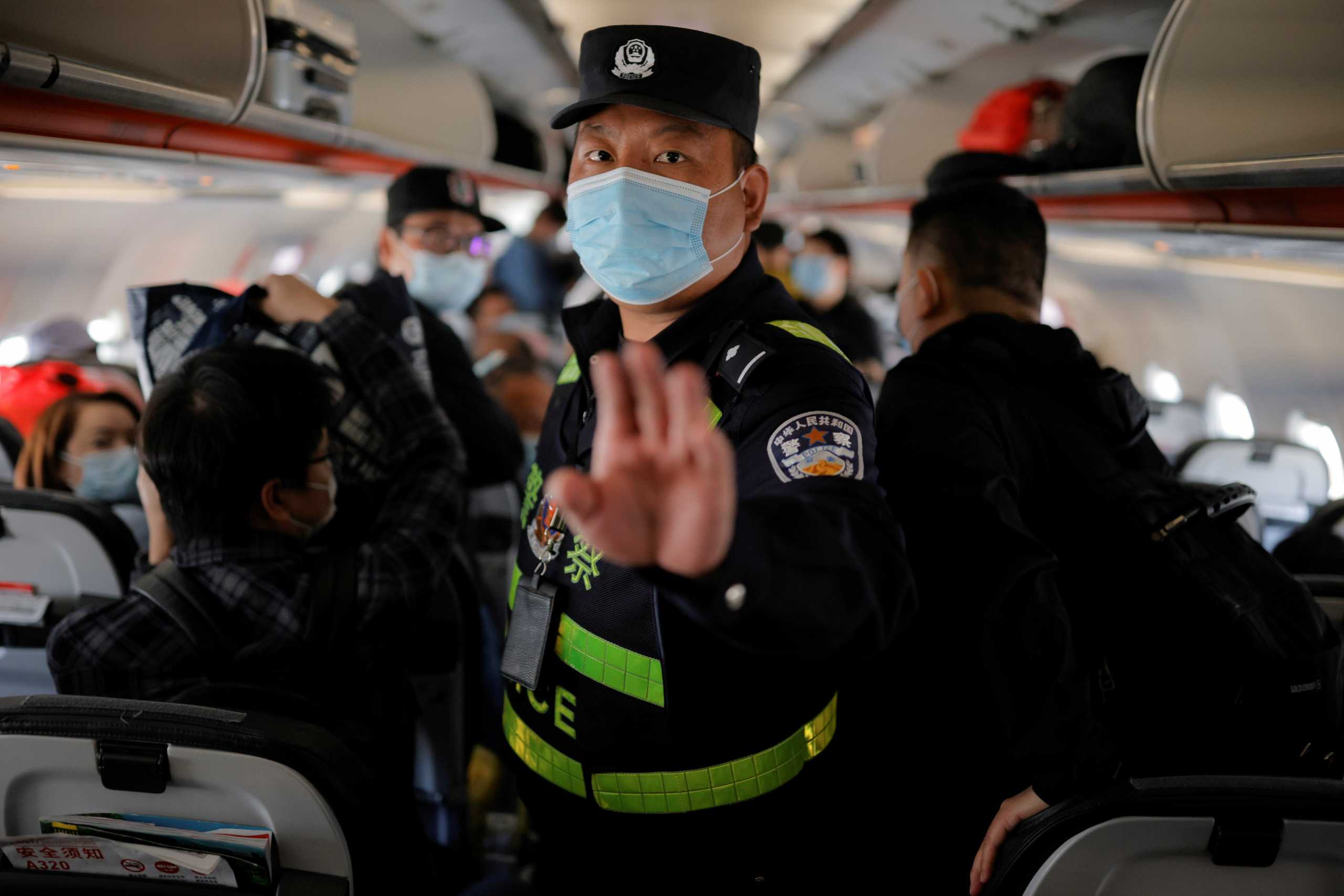 A police officer orders Reuters journalists off the plane before all other passengers without explanation while the plane is parked on the tarmac at Urumqi airport, Xinjiang Uyghur Autonomous Region, China, May 5, 2021. Picture taken May 5, 2021. REUTERS