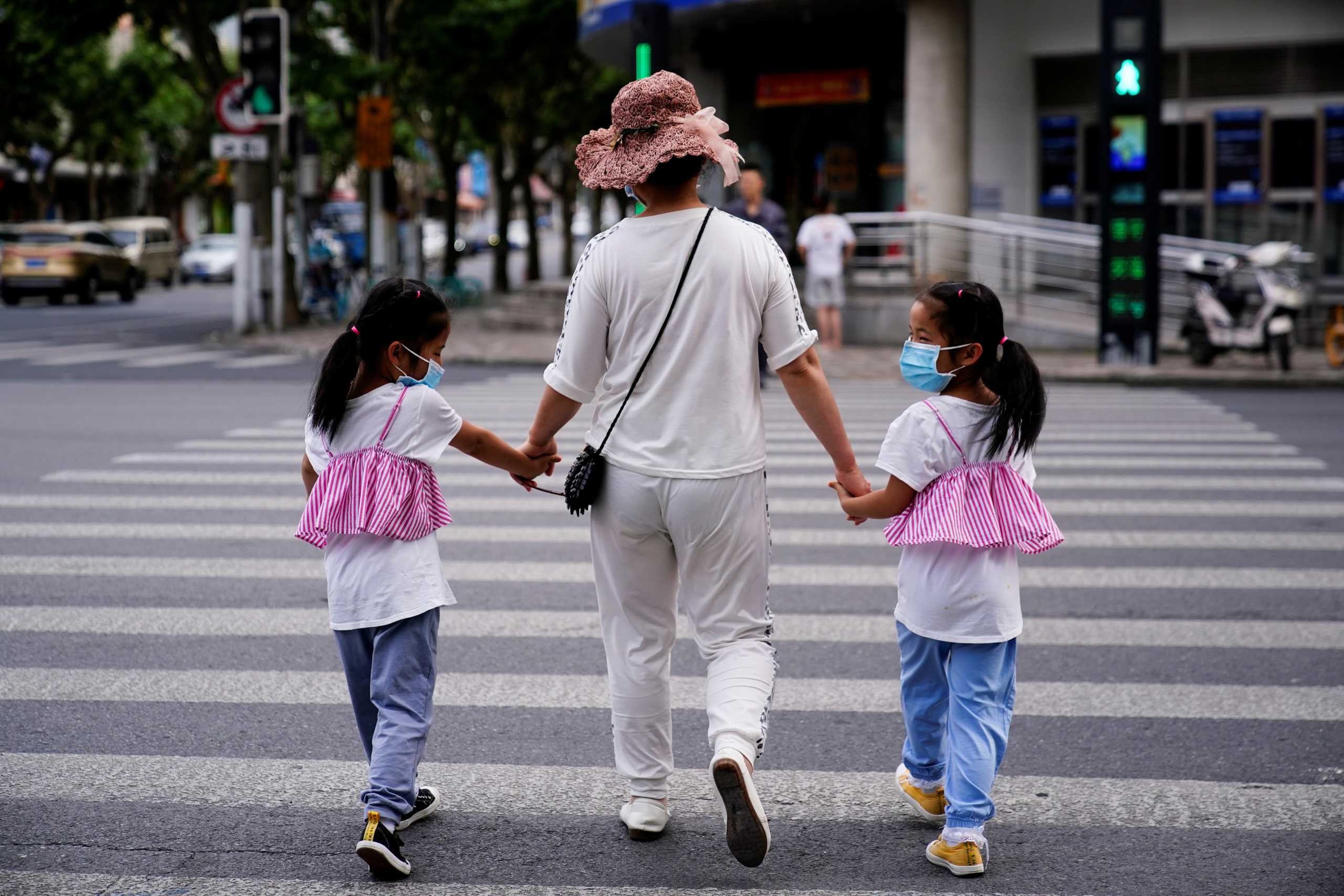 A mother walks with her twin daughters on a street in Shanghai, China June 7, 2021. REUTERS