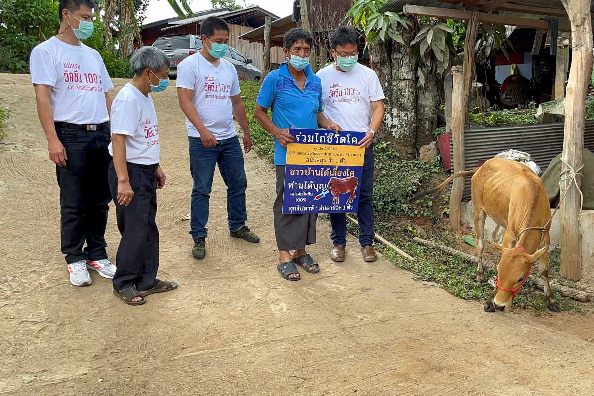 Charan Damrongkiatpana holds up a sign after winning a raffle campaign for inoculated residents to win a live cow per week, in a bid to boost the local the coronavirus disease (COVID-19) vaccination drive in Chiang Mai province, Thailand, June 8, 2021. Picture taken  June 8, 2021. REUTERS