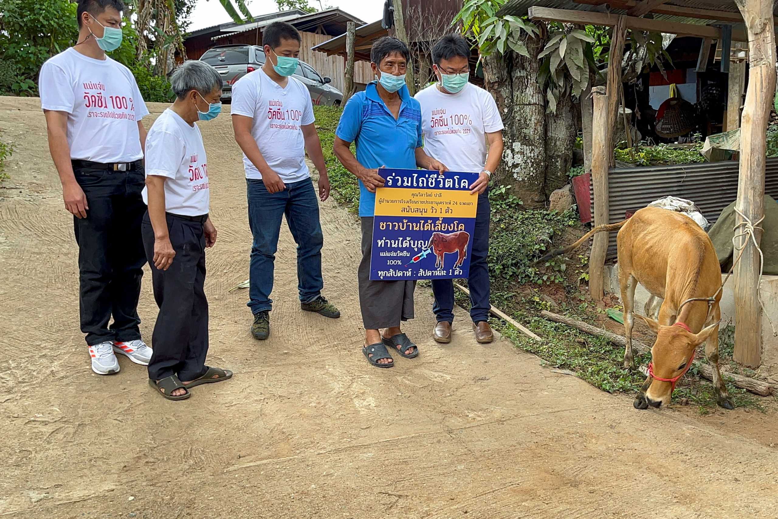 Charan Damrongkiatpana holds up a sign after winning a raffle campaign for inoculated residents to win a live cow per week, in a bid to boost the local the coronavirus disease (COVID-19) vaccination drive in Chiang Mai province, Thailand, June 8, 2021. Picture taken  June 8, 2021. REUTERS