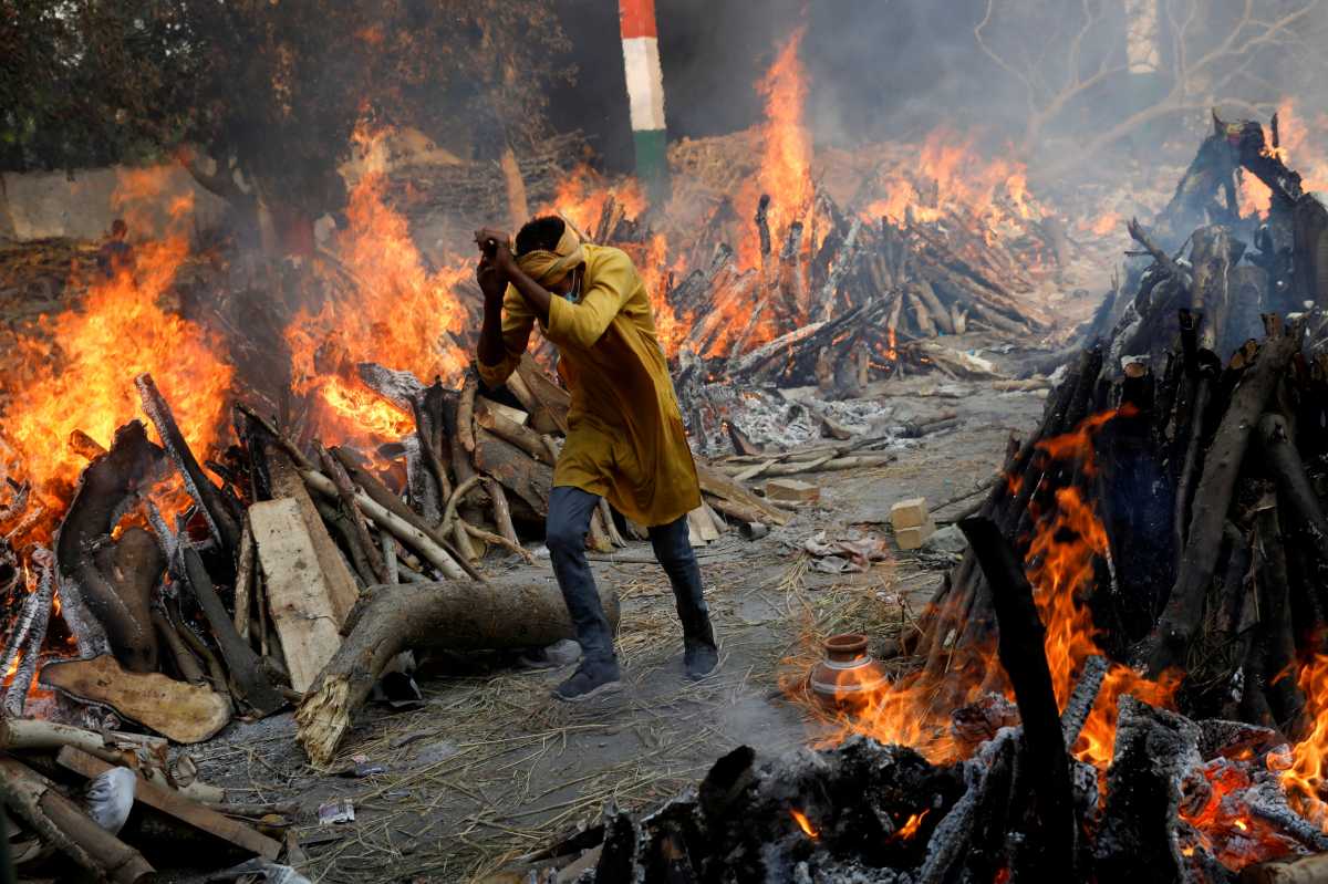FILE PHOTO: A man runs past the burning funeral pyres of those who died from the coronavirus disease (COVID-19), during a mass cremation, at a crematorium in New Delhi, India April 26, 2021. REUTERS