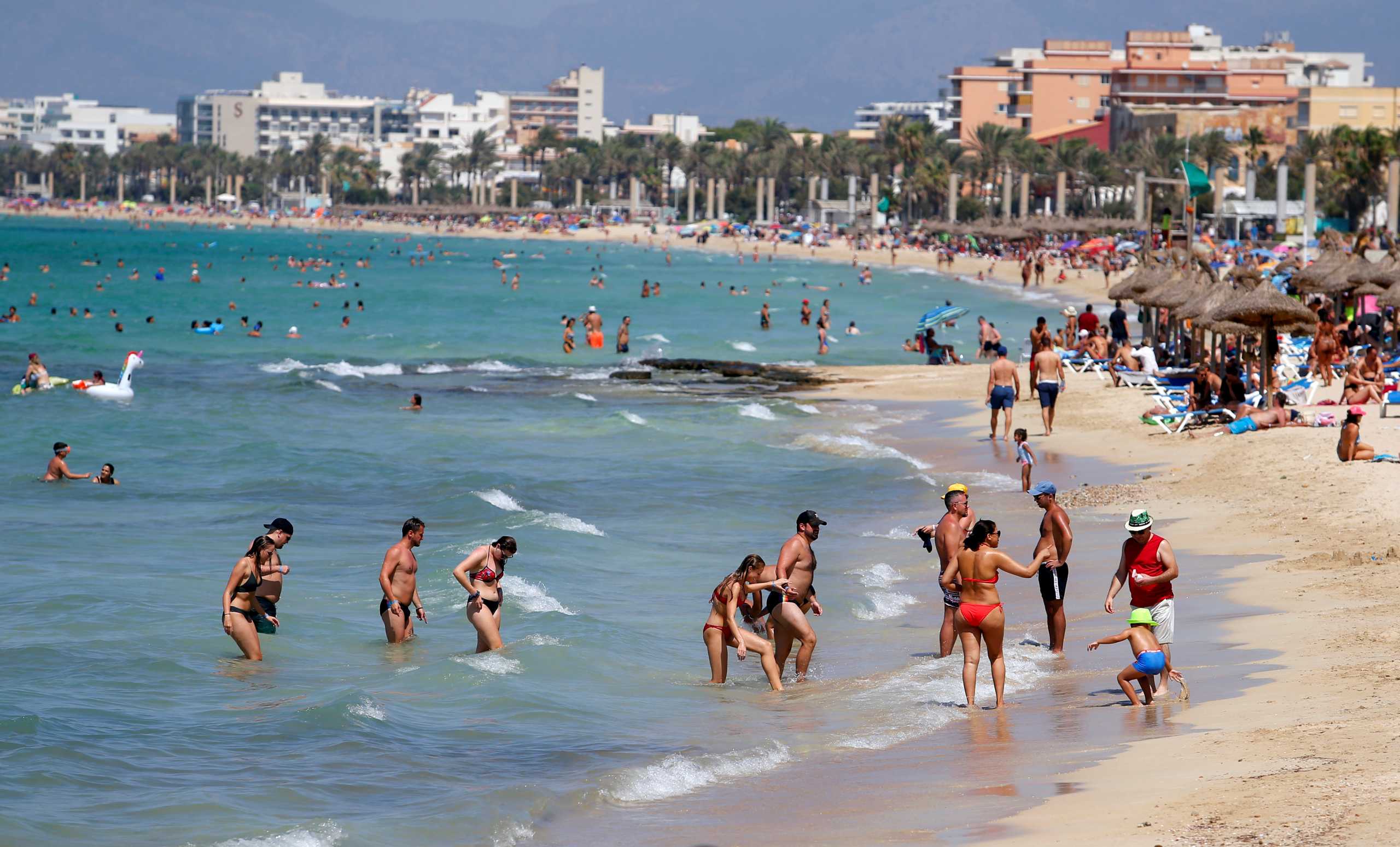 FILE PHOTO: People sunbathe and swim on El Arenal beach, amid the outbreak of the coronavirus disease (COVID-19), in Palma de Mallorca, Spain, August 15, 2020. REUTERS