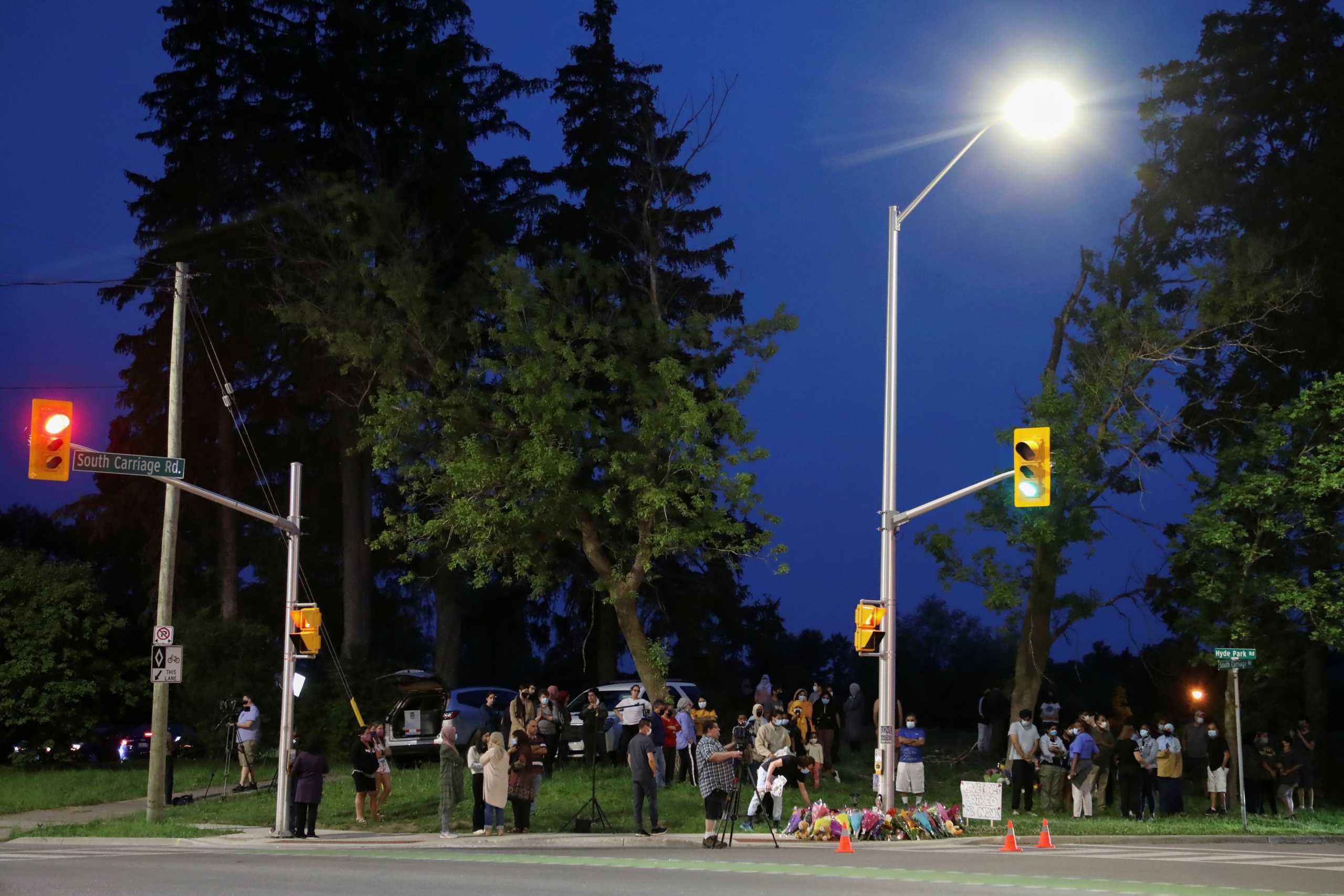 People and members of the media are seen at a makeshift memorial at the fatal crime scene where a man driving a pickup truck jumped the curb and ran over a Muslim family in what police say was a deliberately targeted anti-Islamic hate crime, in London, Ontario, Canada June 7, 2021. REUTERS