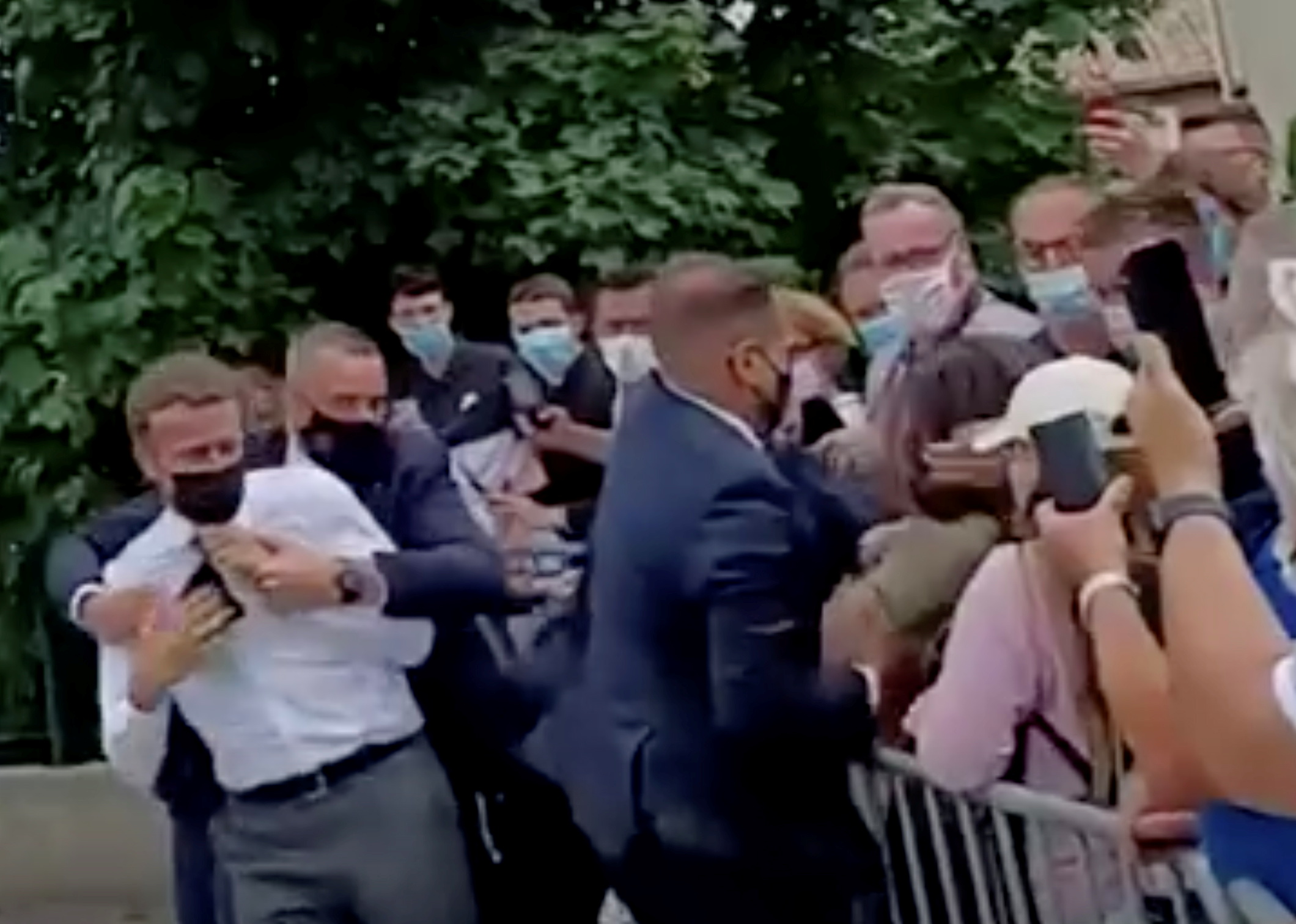 French President Emmanuel Macron is protected by a security member after getting slapped by a member of the public during a visit in Tain-L'Hermitage, France, in this still image taken from video on June 8, 2021. BFMTV