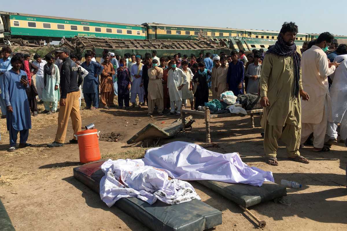 People gather near dead bodies at the site of a collision between two trains in Ghotki, Pakistan June 7, 2021. REUTERS