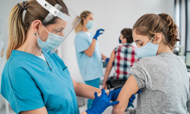 Doctor vaccinating girl. Injecting COVID-19 vaccine into patient's arm
