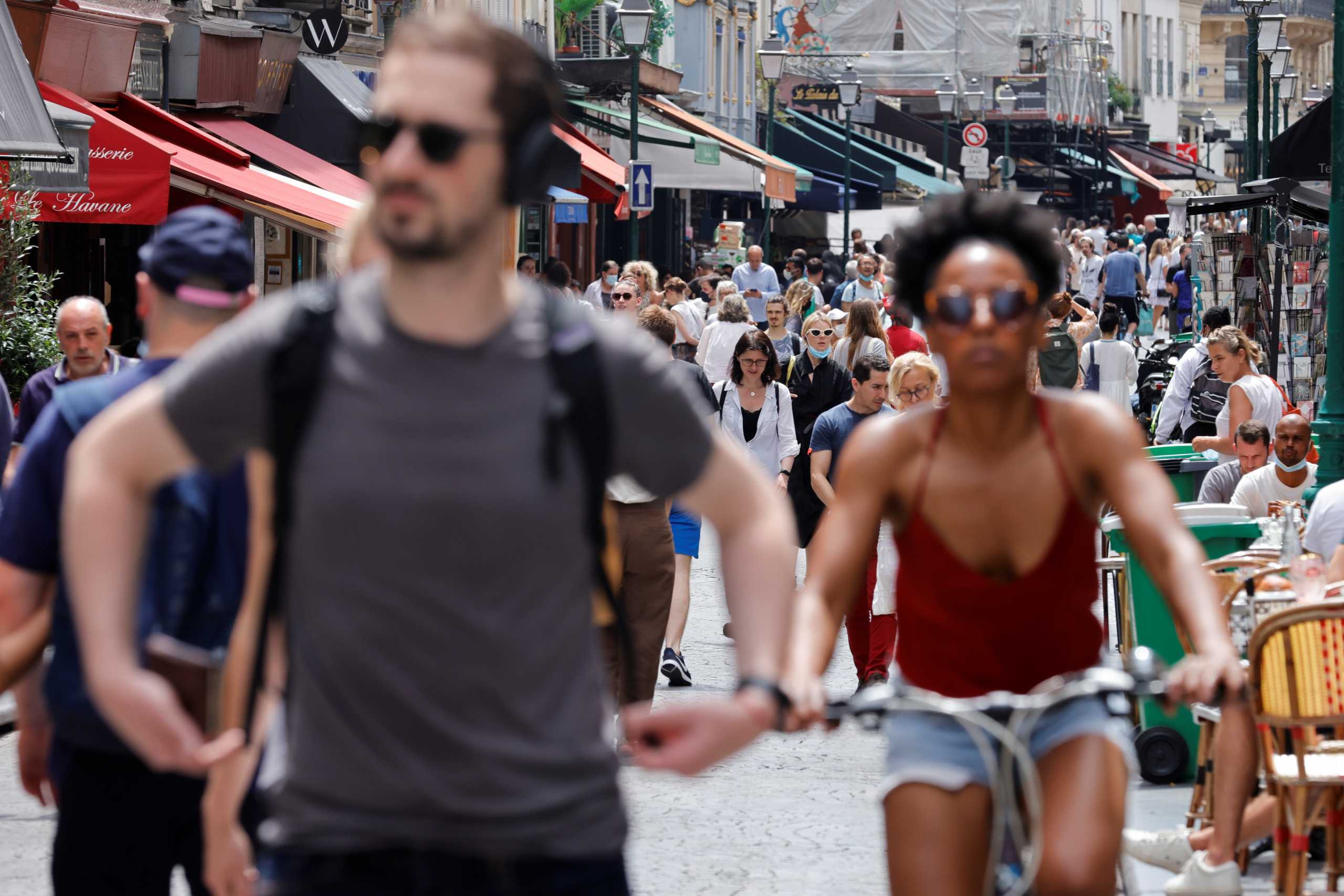 People walk and bike without protective face masks as they are no longer required outdoors amid the coronavirus disease (COVID-19) pandemic, in Paris, France, June 17, 2021. REUTERS