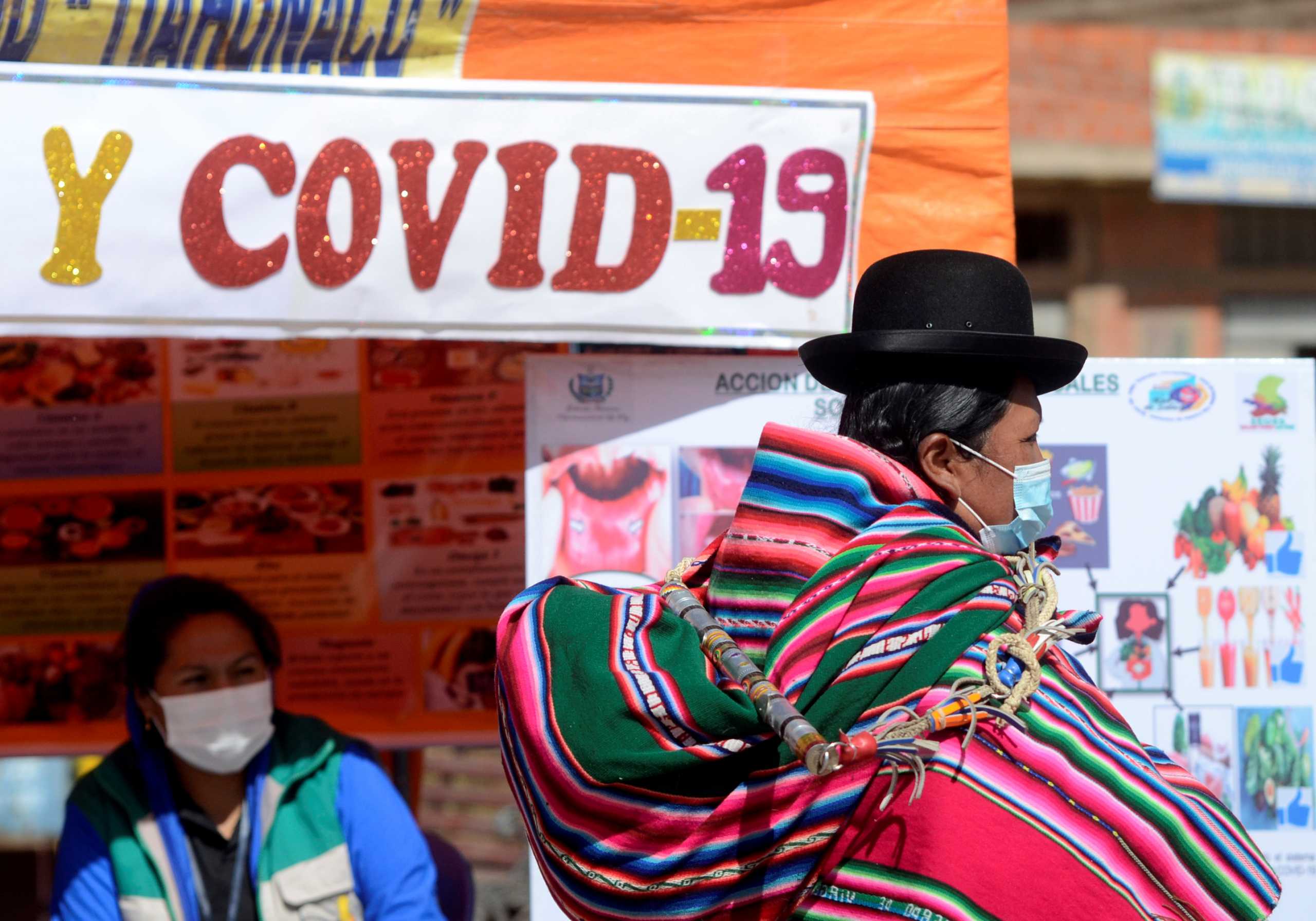 A Bolivian woman walks past a stand that provides information on diets in relationship to the coronavirus disease (COVID-19), as authorities have started to vaccinate people who make a living crossing the border between Bolivia and Peru, in Desaguadero, Bolivia May 21, 2021. Picture taken May 21, 2021. REUTERS