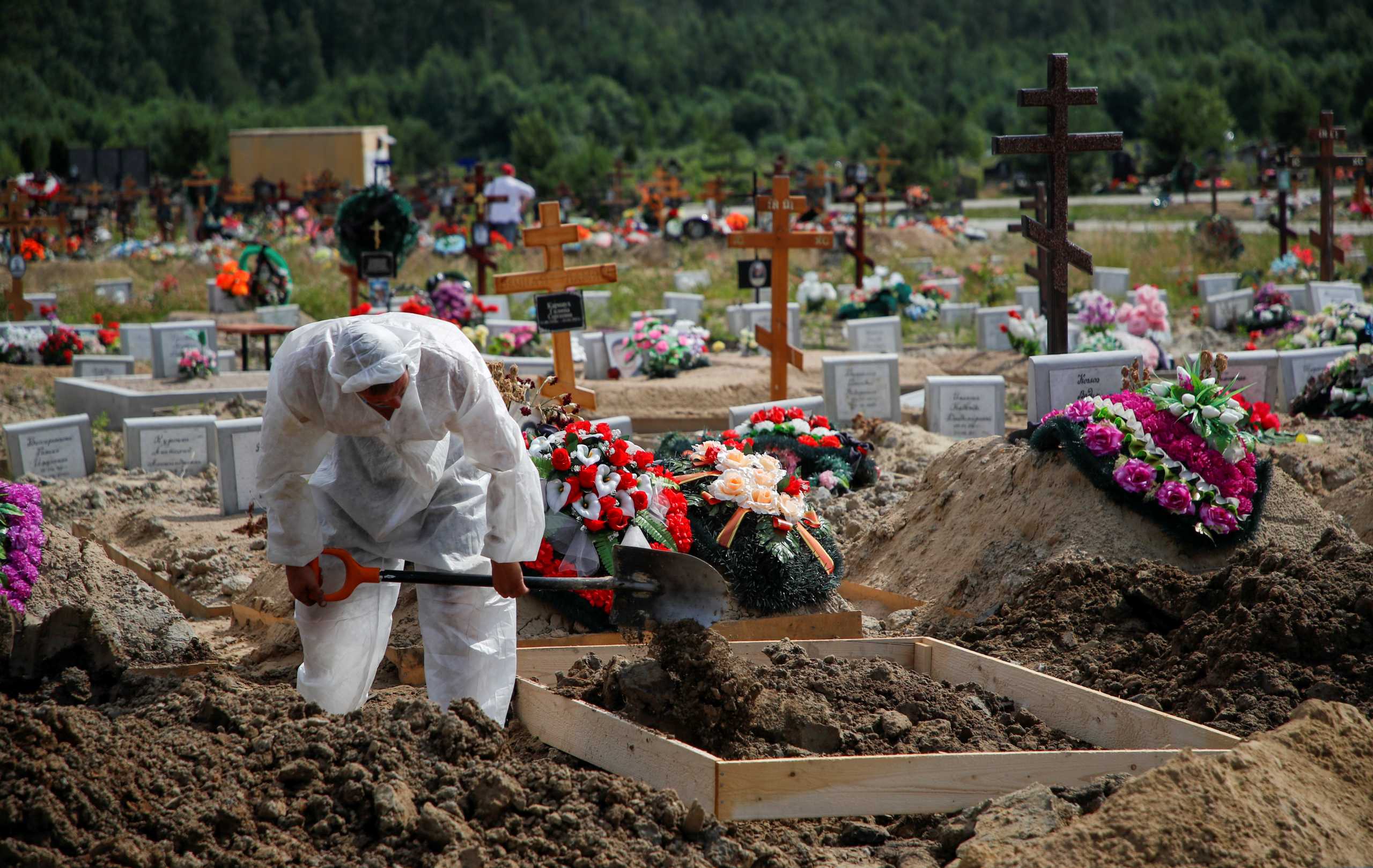 A grave digger wearing personal protective equipment (PPE) as a preventive measure against the coronavirus disease (COVID-19) buries a person at a graveyard on the outskirts of Saint Petersburg, Russia June 25, 2021. REUTERS