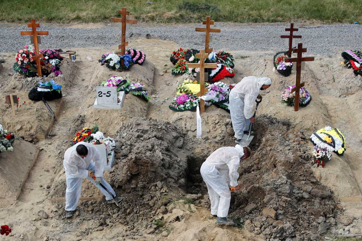 Grave diggers wearing personal protective equipment (PPE) as a preventive measure against the coronavirus disease (COVID-19) bury a person at a graveyard on the outskirts of Saint Petersburg, Russia June 25, 2021. REUTERS