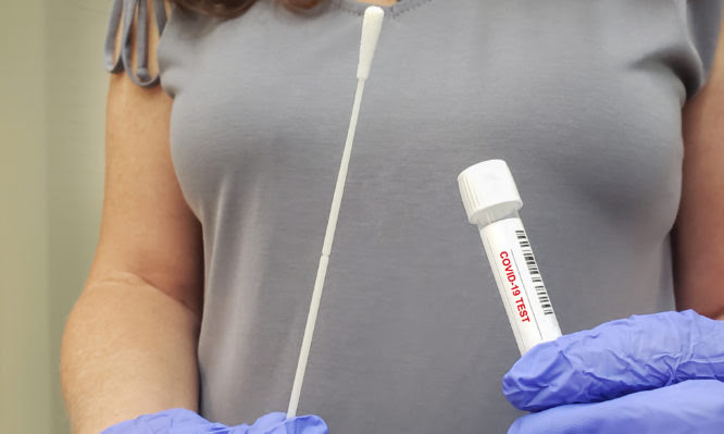 Woman holding self testing self-administered swab and medical tube for Coronavirus COVID-19, before being self tested at office or home