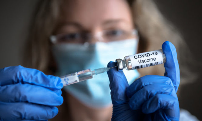 COVID-19 vaccine in researcher hands, female doctor holds syringe and bottle with vaccine for coronavirus cure. Concept of corona virus treatment, injection, shot and clinical trial during pandemic.