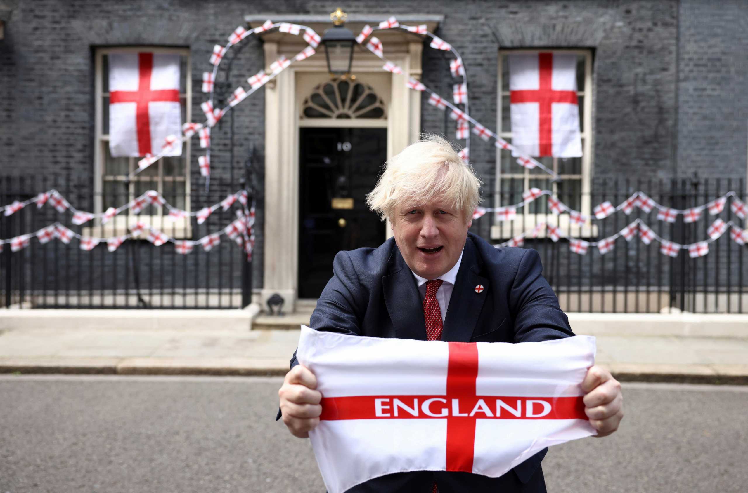 Britain's Boris Johnson poses on Downing Street with a flag ahead of the Euro 2020 final, in London, Britain July 9, 2021. REUTERS