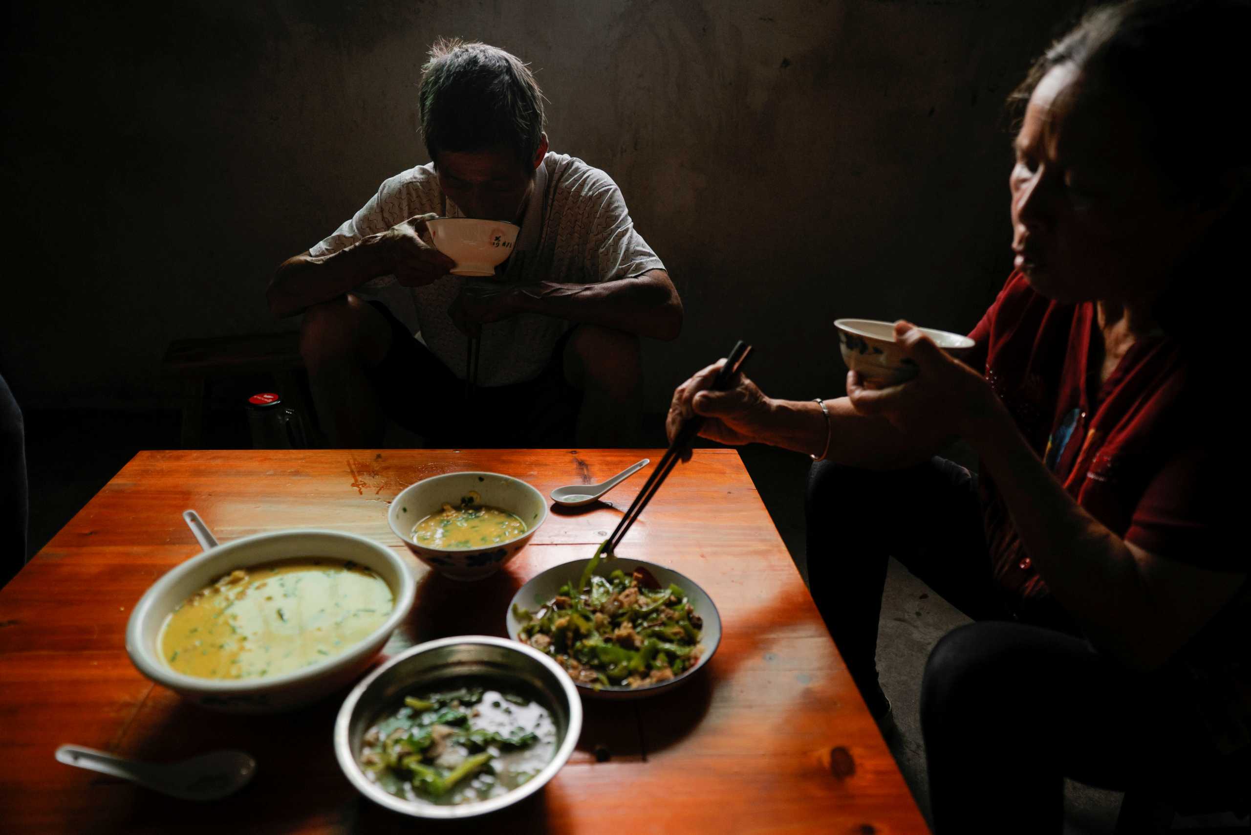 Farmers eat home cooked food in their kitchen in the village of Yangchao in Liping County, Guizhou province, China, June 11, 2021. Picture taken June 11, 2021.  REUTERS