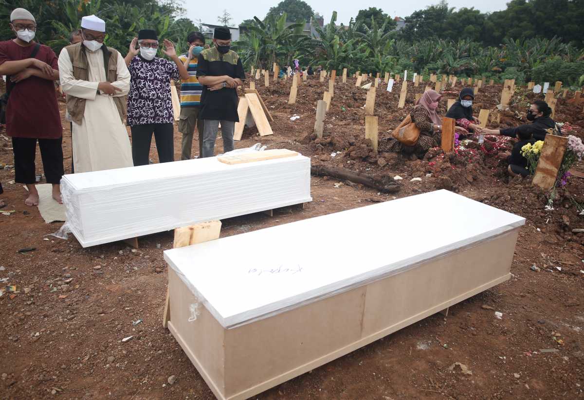 Relatives take part in a funeral prayer by the coffin at a burial area provided by the government for coronavirus disease (COVID-19) victims, as cases surge in South Tangerang, on the outskirts of Jakarta, Indonesia July 13, 2021. Antara Foto