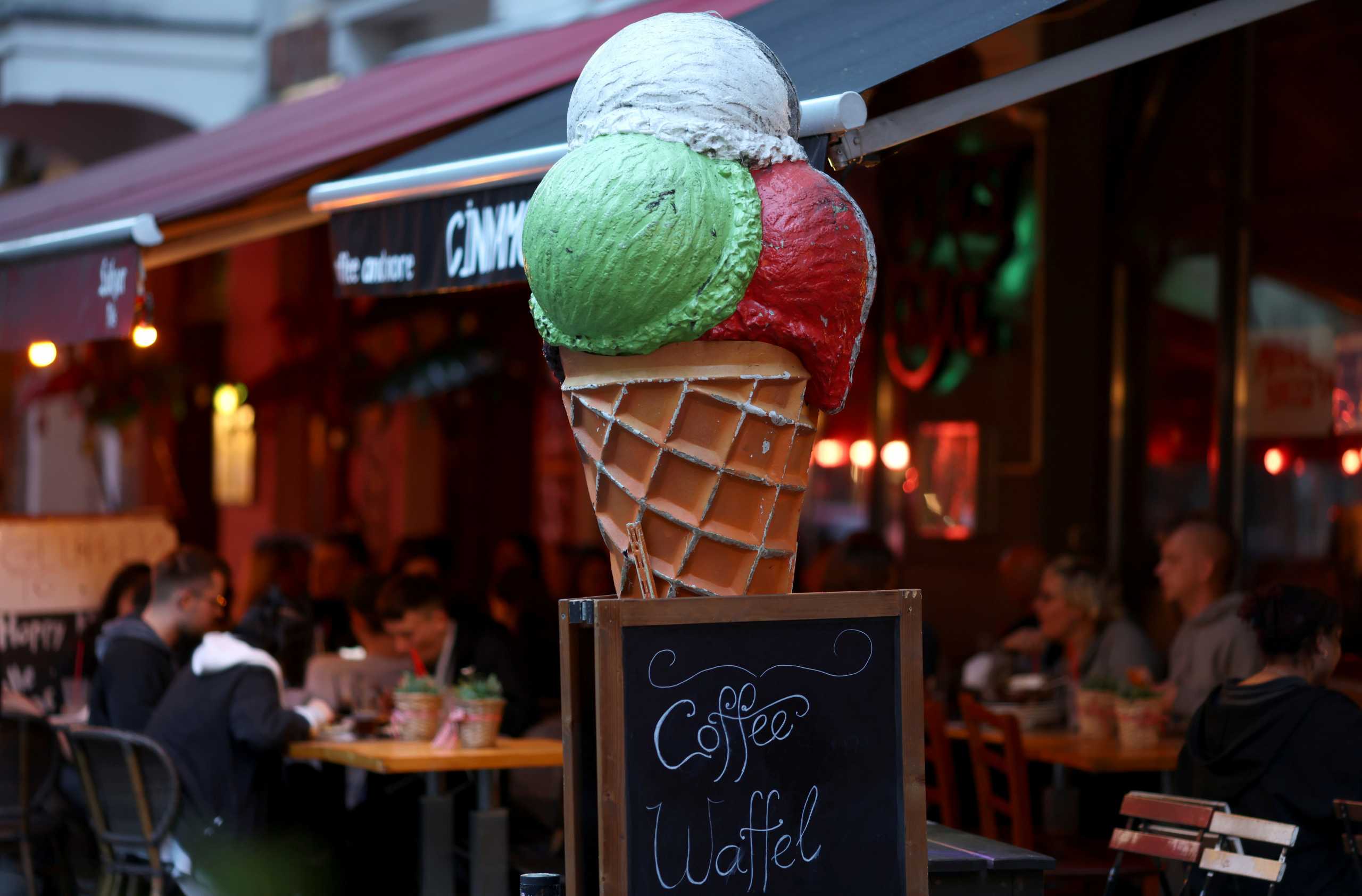 FILE PHOTO: People enjoy the evening at a tarrace of a bar at Simon Dach Street, as cafes, bars and restaurants reopen their terraces after being closed down for months, amid the coronavirus disease (COVID-19) outbreak, in Berlin, Germany, May 21, 2021. REUTERS