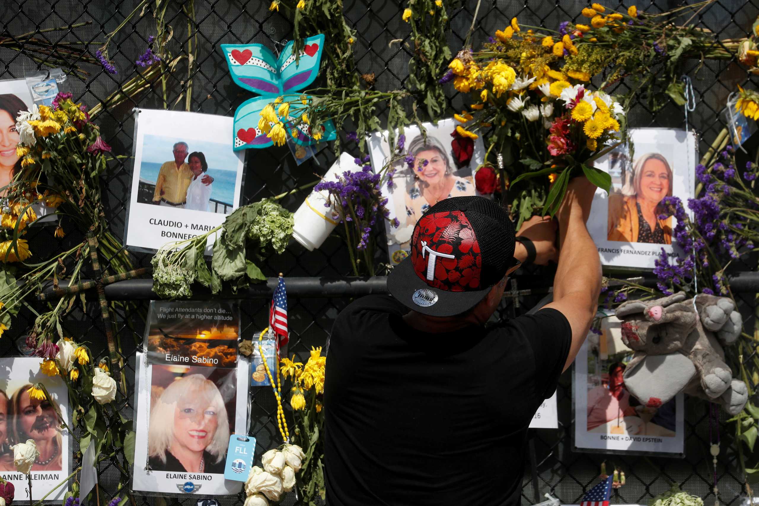 FILE PHOTO: A man places flowers on a makeshift memorial for the victims of the Surfside's Champlain Towers South condominium collapse in Miami, Florida, U.S., July 8, 2021. REUTERS