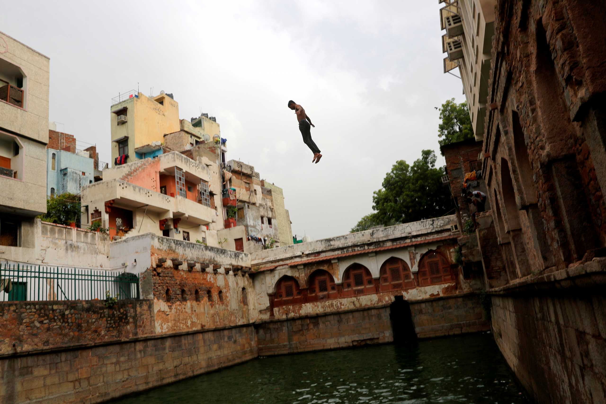 A boy jumps into a stepwell, built inside the shrine of Sufi Saint Nizamuddin Auliya, to cool off on a hot summer day in New Delhi, India, July 2, 2021. REUTERS