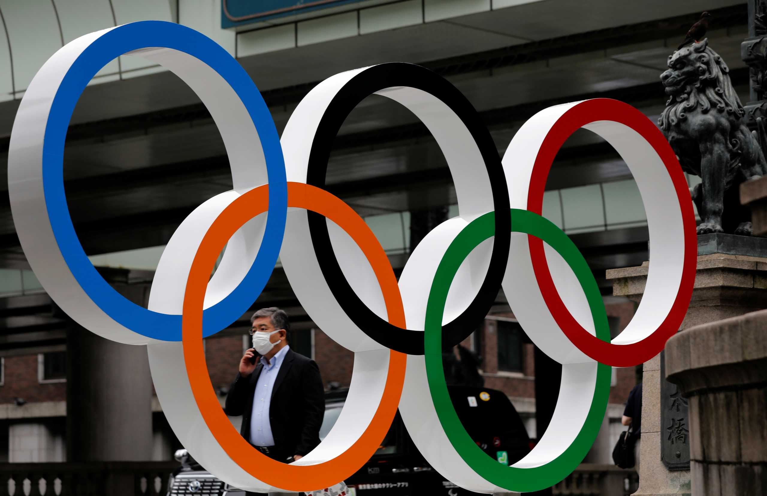 A man wearing a protective mask, following the coronavirus disease (COVID-19) outbreak, walks past Olympic Ring promoting Tokyo 2020 Olympic Games in Tokyo, Japan, July 12, 2021.   REUTERS