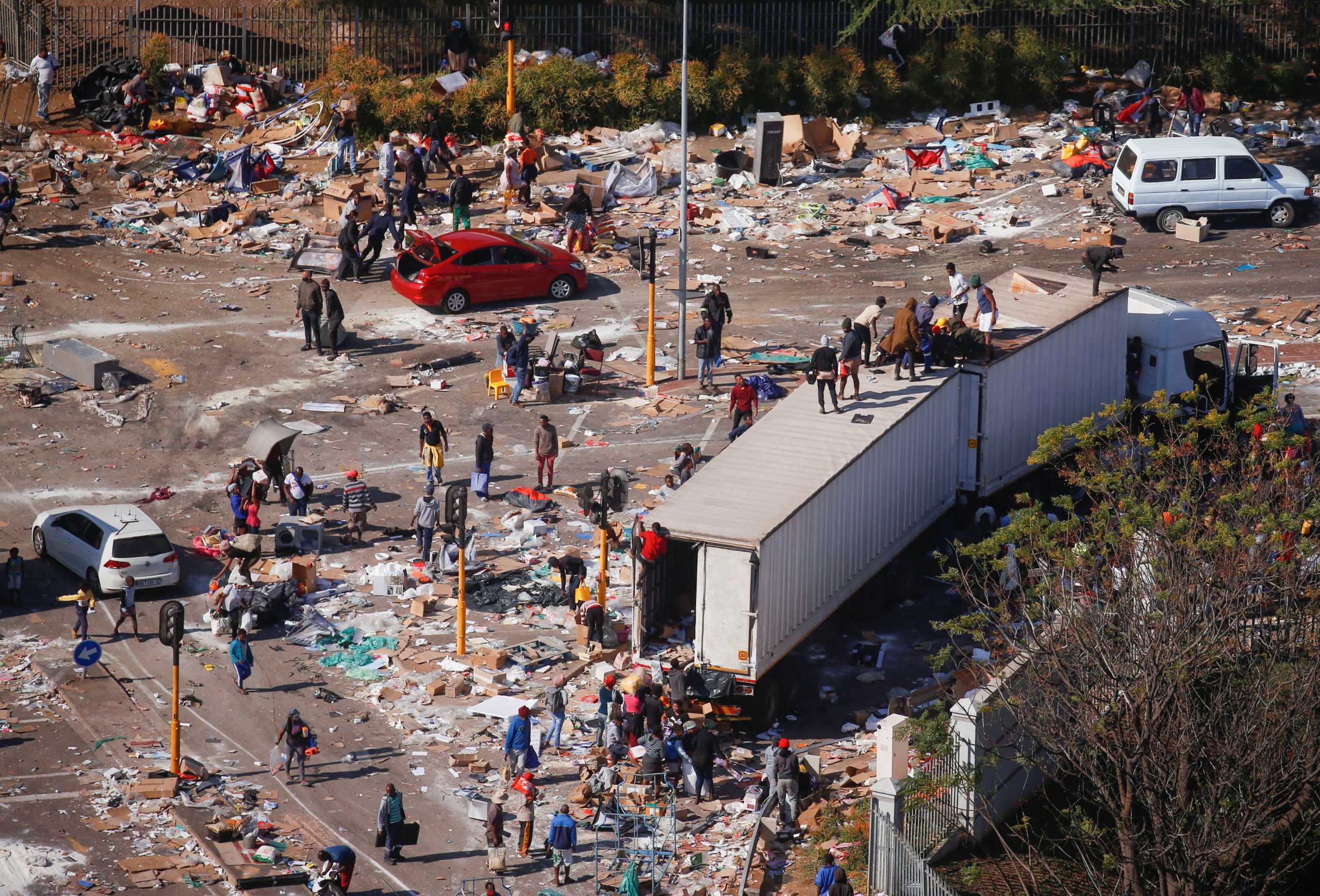 People loot an area near a burning warehouse after violence erupted following the jailing of former South African President Jacob Zuma, in Durban, South Africa, July 14, 2021. REUTERS