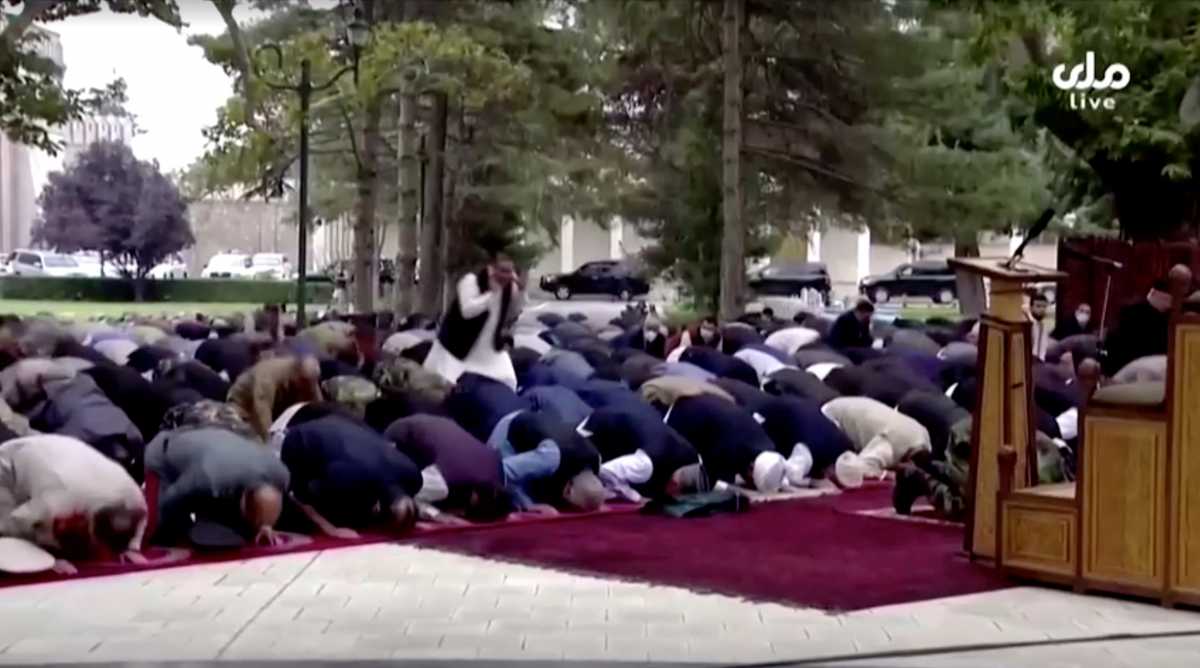A man covers his ears as he reacts to the sounds of rocket explosions landing near the presidential palace, during an outdoor gathering for Eid al-Adha prayers attended by President Ashraf Ghani (front row), in the palace compound, in Kabul, Afghanistan, July 20, 2021, in this still image taken from TV footage. RTA