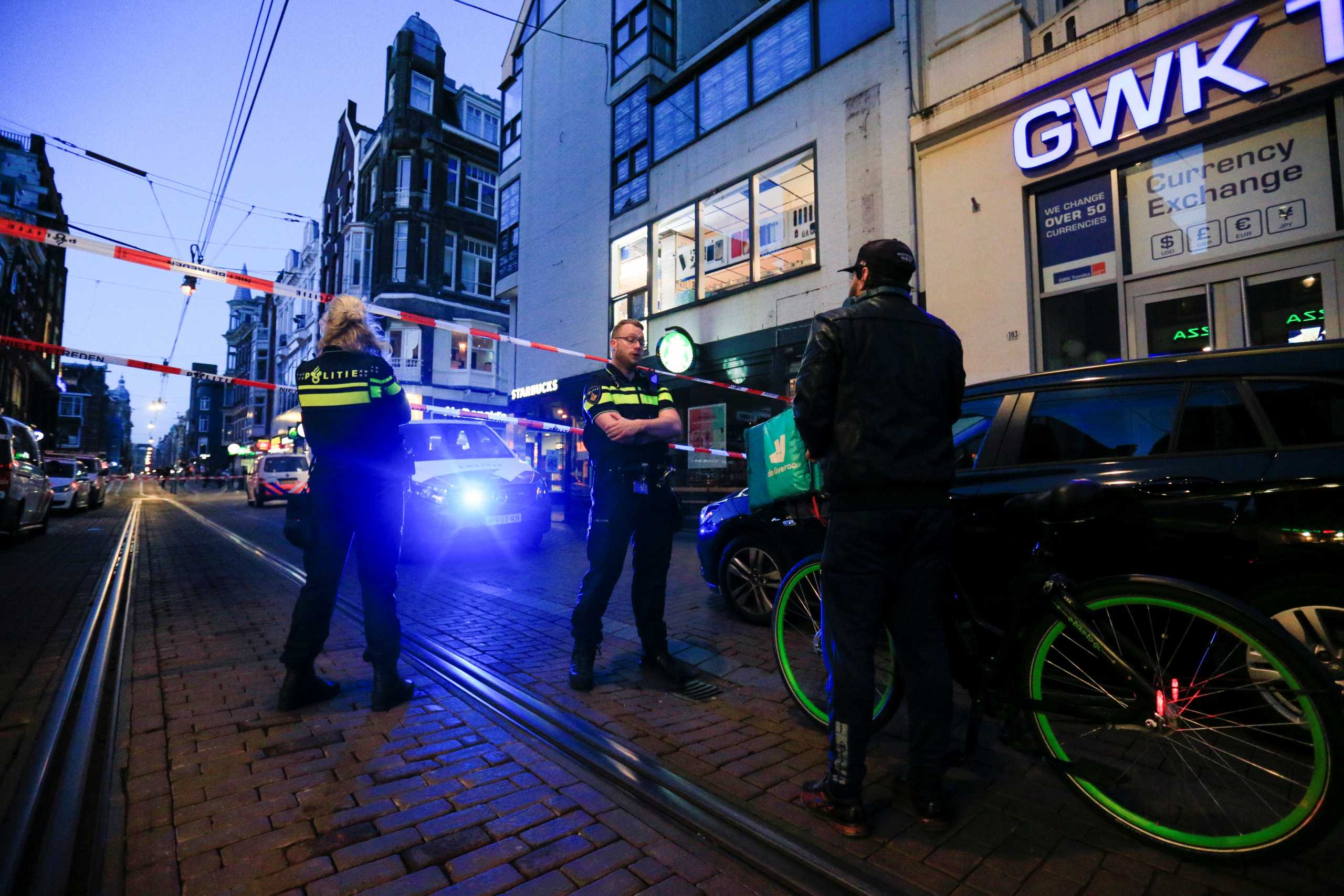 Police officers talk to a person as they stand guard in the area where Dutch celebrity crime reporter Peter R. de Vries, known for his reporting on some of the most renowned criminals in the Netherlands, was reportedly shot and seriously injured, in Amsterdam, Netherlands, July 6, 2021. REUTERS