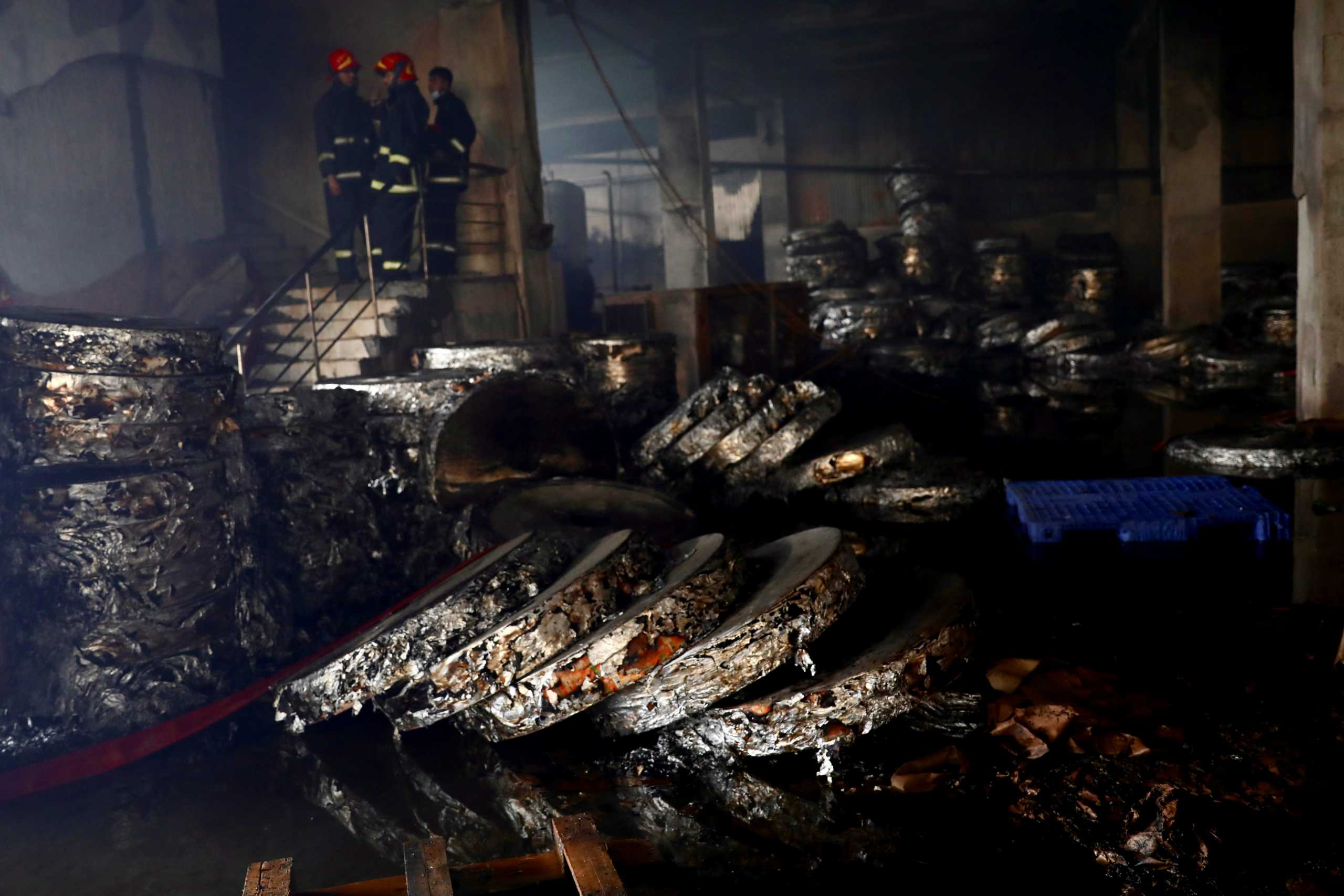 Firefighters stand inside a Hashem Foods Ltd factory as burnt items are seen after a fire broke out, in Rupganj, Narayanganj district, on the outskirts of Dhaka, Bangladesh, July 9, 2021. REUTERS